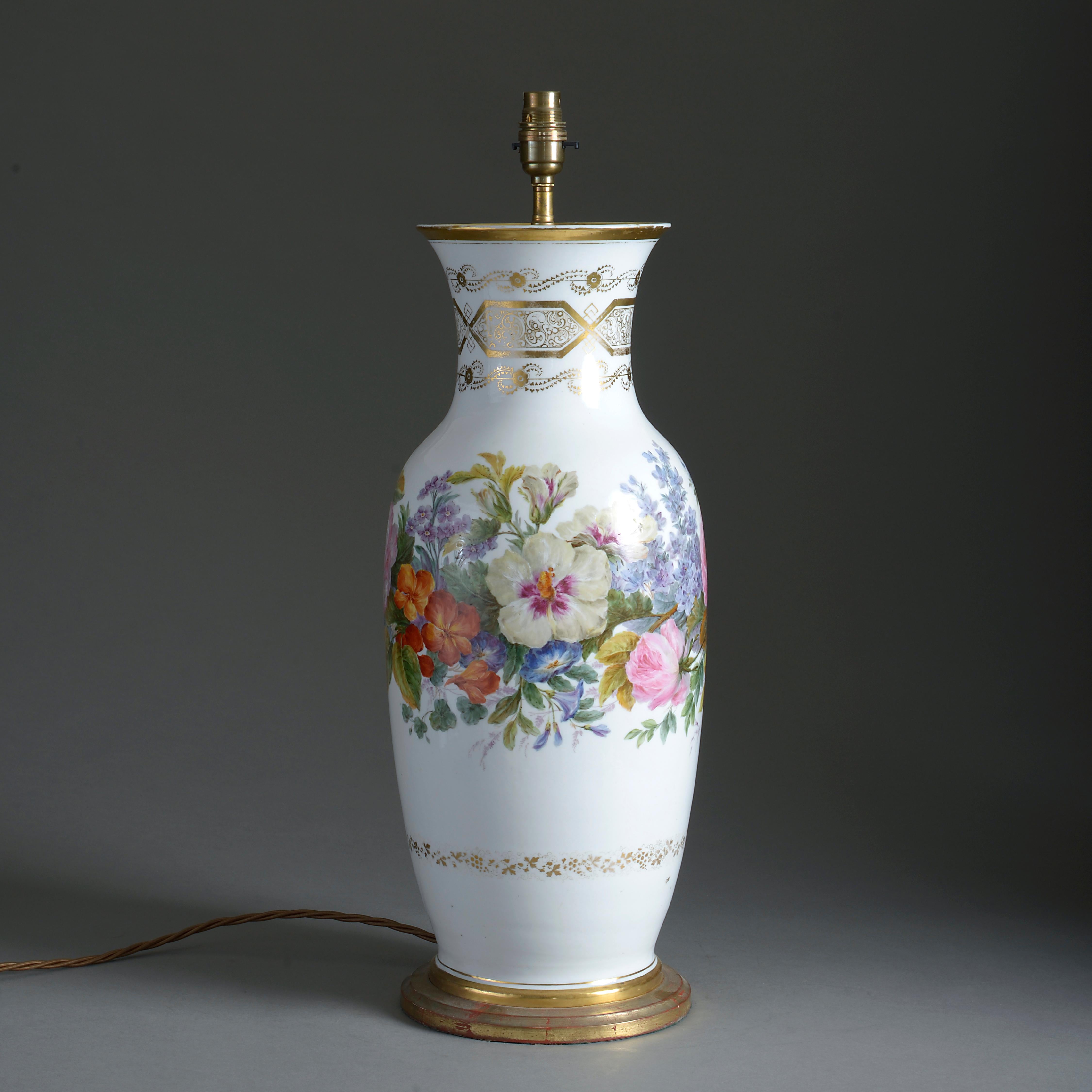 A large mid-19th century porcelain vase, the body decorated with gilt strapwork and a band of floral decoration in polychrome glazes upon a white ground. Raised on a giltwood base and wired as a table lamp.

Height dimension refers to antique