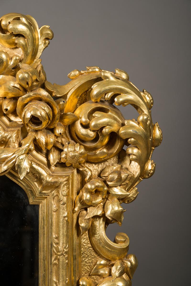 A magnificent 19th century French Rococo style carved giltwood figural palatial mirror. This imposing mirror is decorated in the Rococo style with an array of carved fruits and flowers, each side with a carved cherub playing a musical instrument.