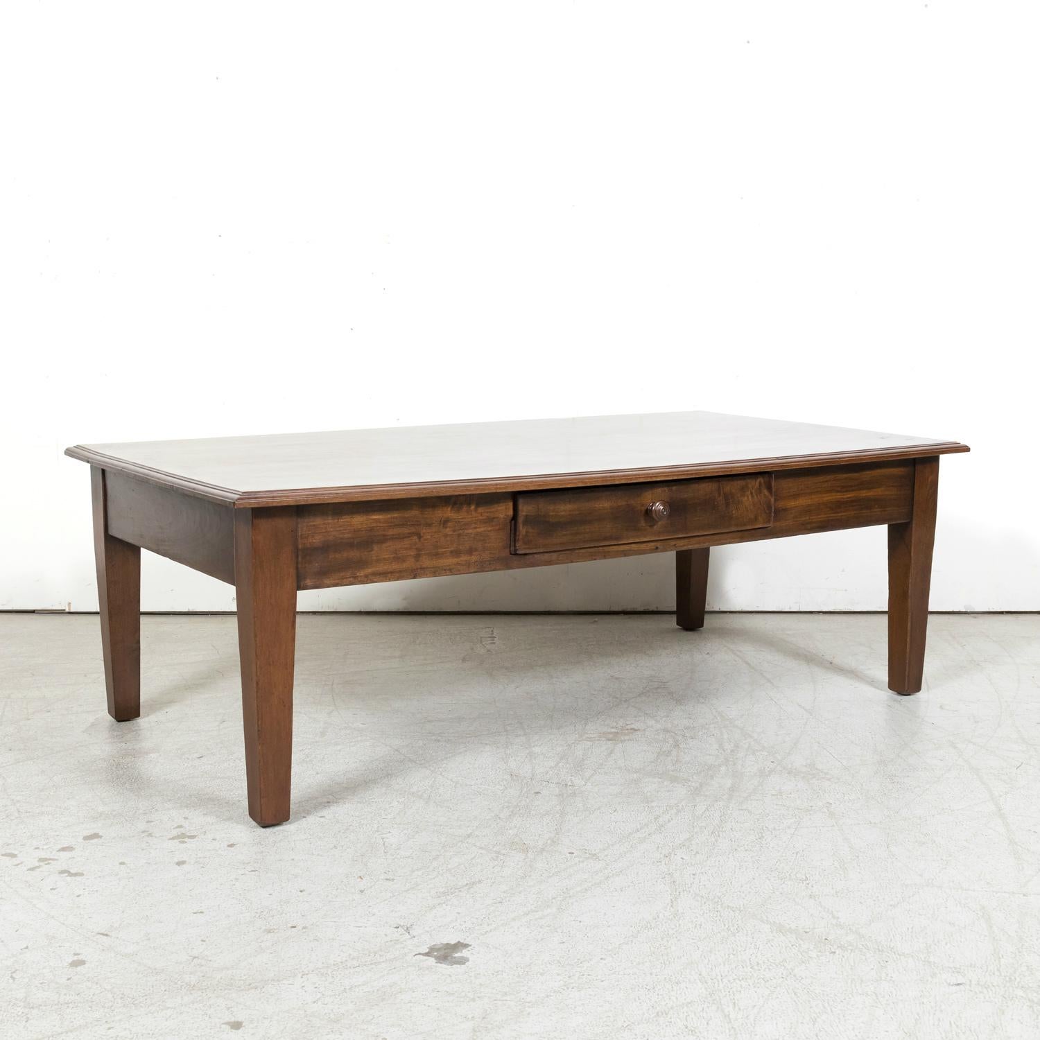 A large 19th century French Country coffee table handcrafted of solid walnut in the beautiful hills known as Les Alpes Mancelles in the Normandy region, circa 1890s. Having a rich patina and distinctive grain pattern, this rustic table's design is