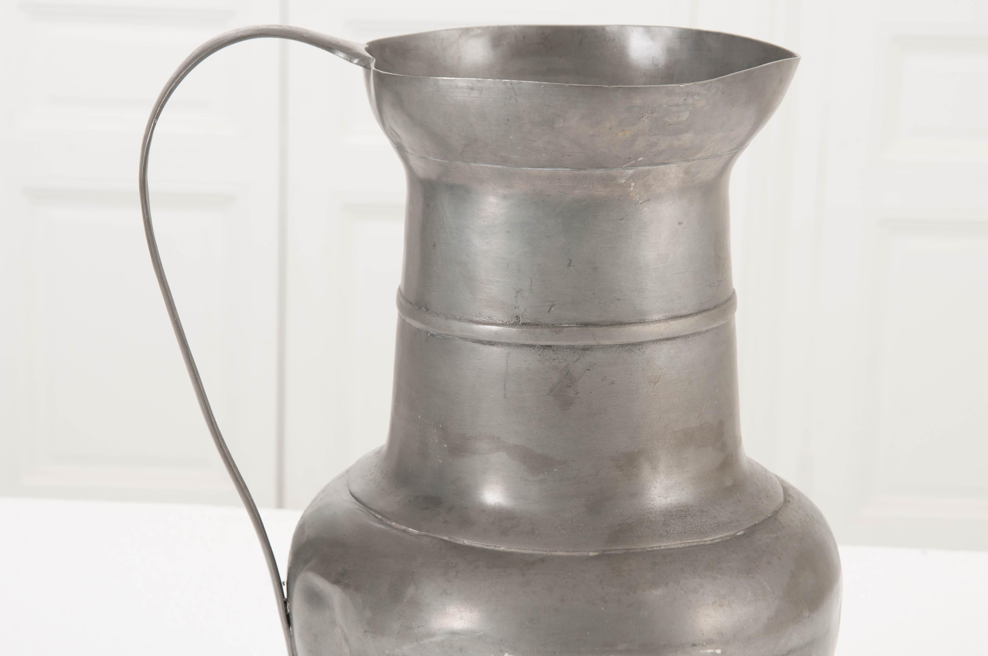 This sizable pewter pitcher was made in Scotland, towards the end of the 19th century. The solid metal vessel has acquired a weathered patina that pewter acquires so well, softening the metallic finish and making for a beautiful antique. Accessorize