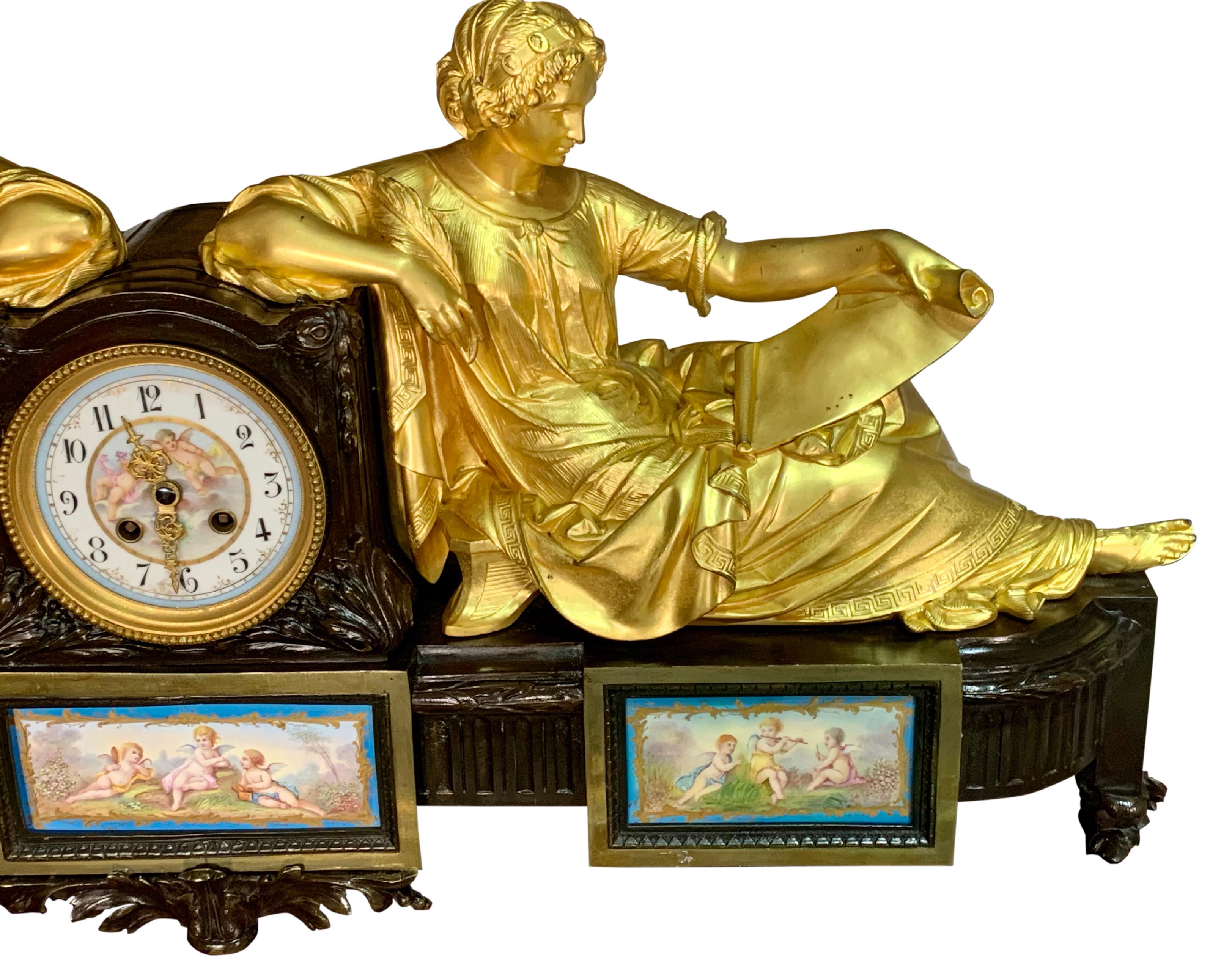 A magnificent French mantel clock in patinated bronze and original ormolu. Modeled with figures of two classically dressed females sitting back to back against the clock drum and reading from ormolu book and scroll. The porcelain dial painted with