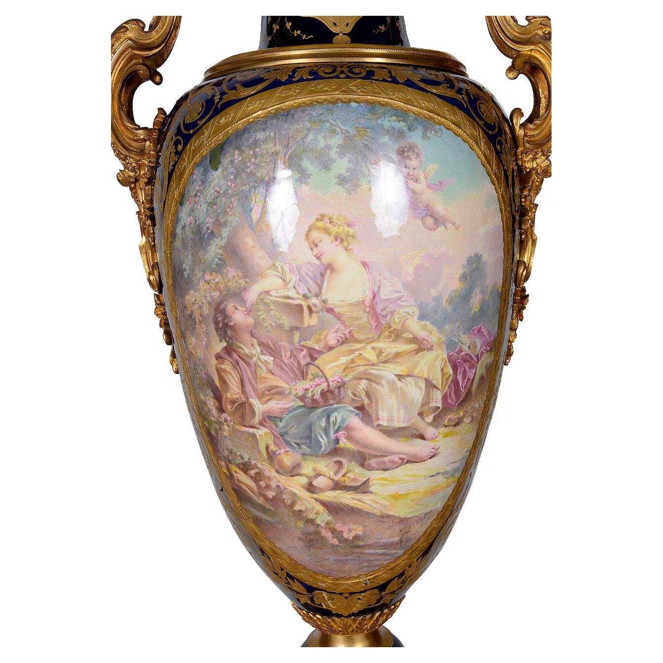 Impresionante jarrón con tapa de porcelana de estilo Luis XVI Sevres de finales del siglo XIX. Con un fondo clásico azul cobalto, detalles dorados de volutas, molduras y asas. Una escena romántica de amantes reclinados, bellamente pintada a mano,