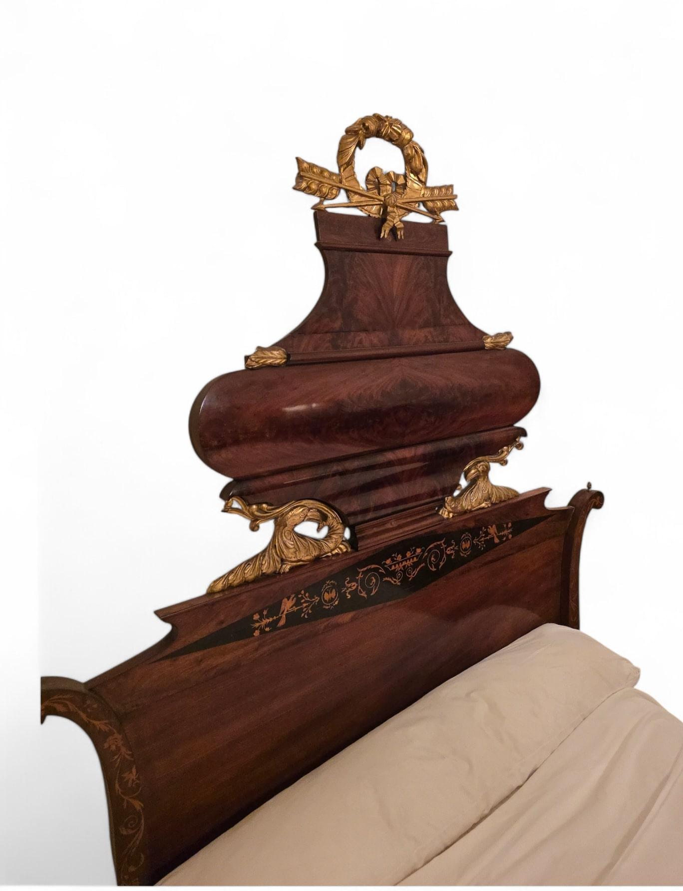 This grand Spanish bed from the early 19th century is a masterpiece of craftsmanship, blending exotic and fruitwood with intricate marquetry and gilded details. The frame features exquisite vegetal motifs in lemonwood marquetry, adding elegance and