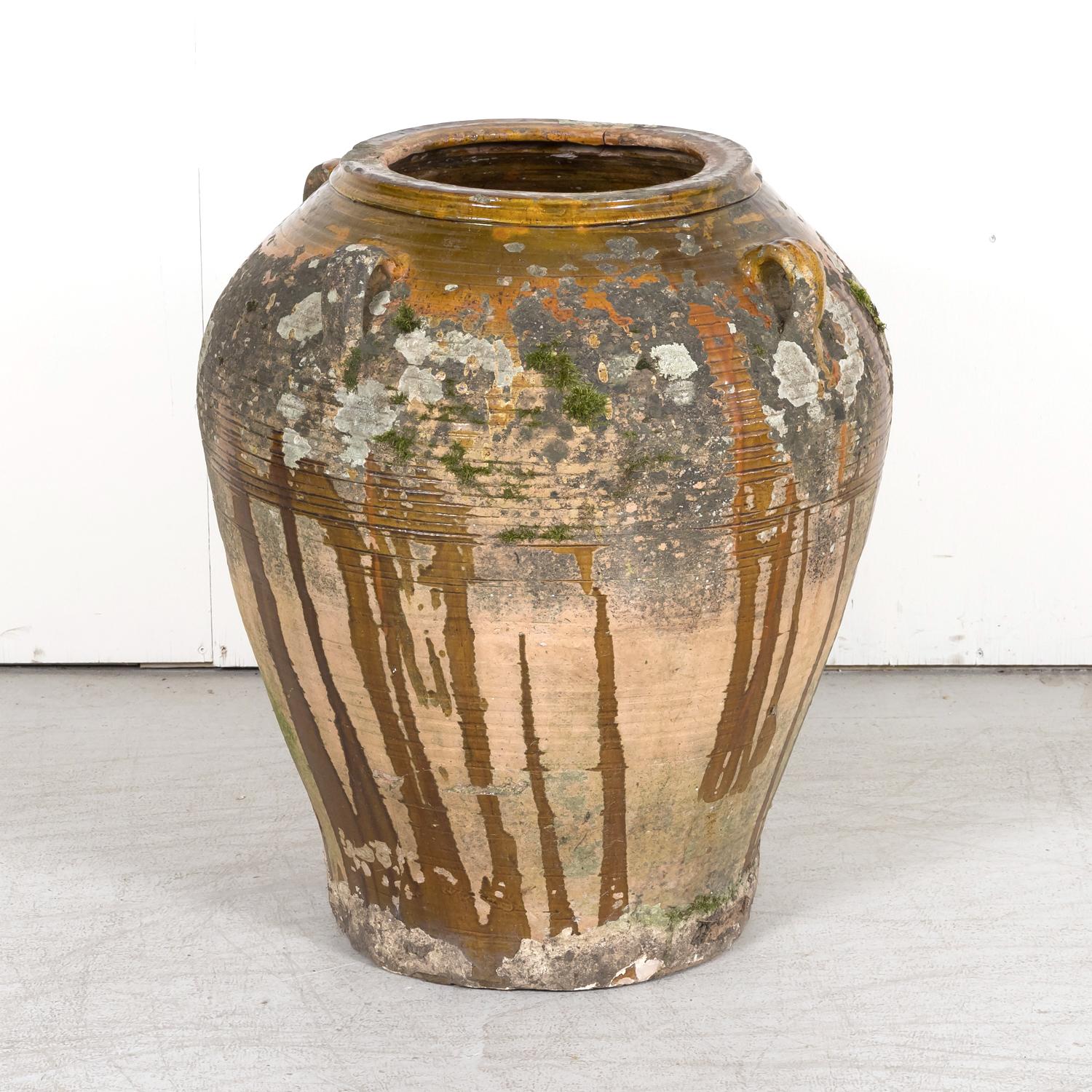 A large antique 19th century traditional Spanish terracotta orza or olive jar handmade in the province of Tarragona in the Catalonia region, circa 1880s. This beautiful jar features a dark caramel interior glaze with a semi-glazed exterior having