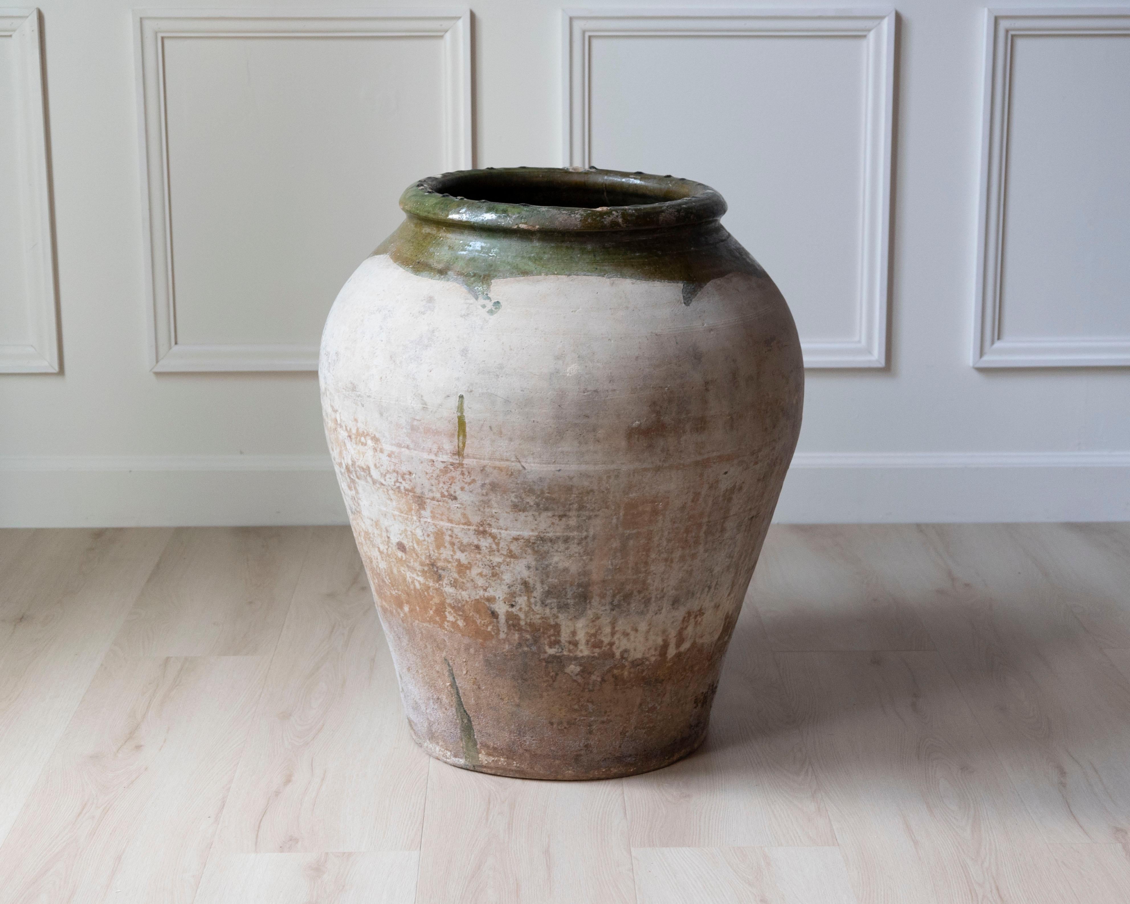 Cette monumentale jarre espagnole en terre cuite du 19e siècle possède à la fois un caractère rustique et une présence architecturale. Traditionnellement utilisé pour stocker l'huile d'olive, les céréales ou le vin, ce récipient a été fabriqué à la