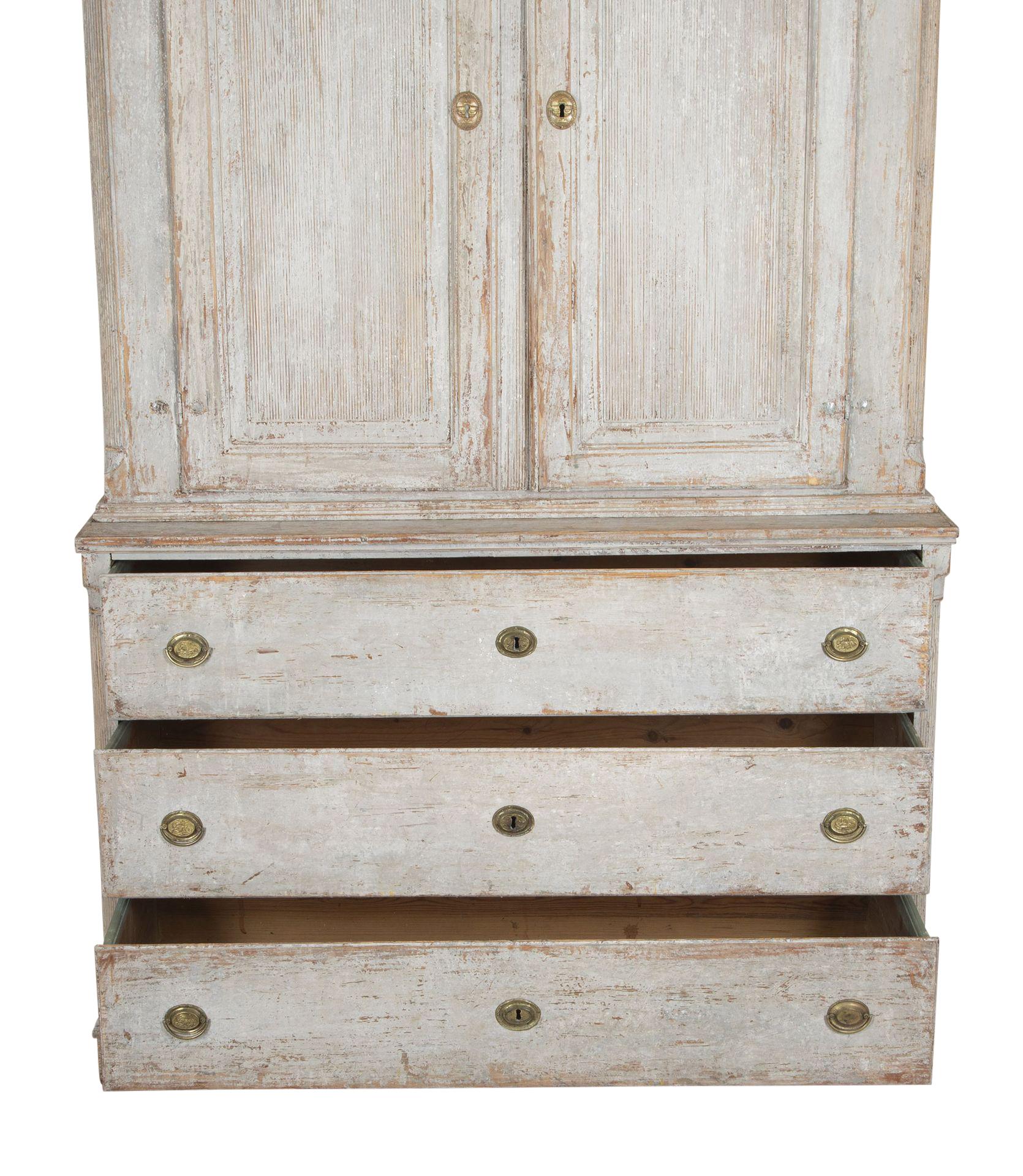 Well carved large early 19th Century Swedish Gustavian two part cupboard from the islands of Gotland. 
Two doors with carved reeded decoration, opening to useful storage and below, three drawers. Repainted in soft grey.
Circa 1820.