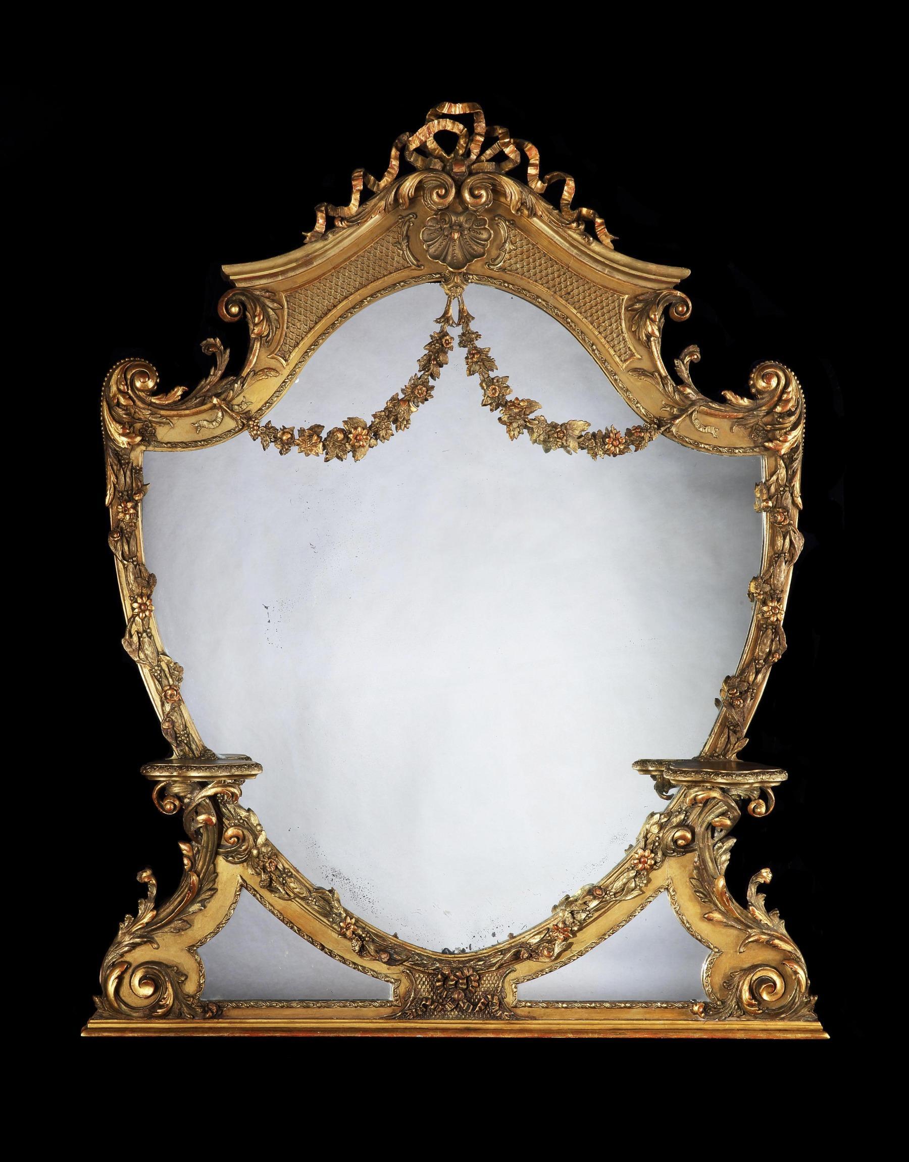An unusual shield or cartouche shaped 19th century Victorian giltwood and gesso overmantel mirror of large proportions standing 6ft tall, English, circa 1880. Of neoclassical cartouche shaped form, the original mirror plate within a scroll, flower