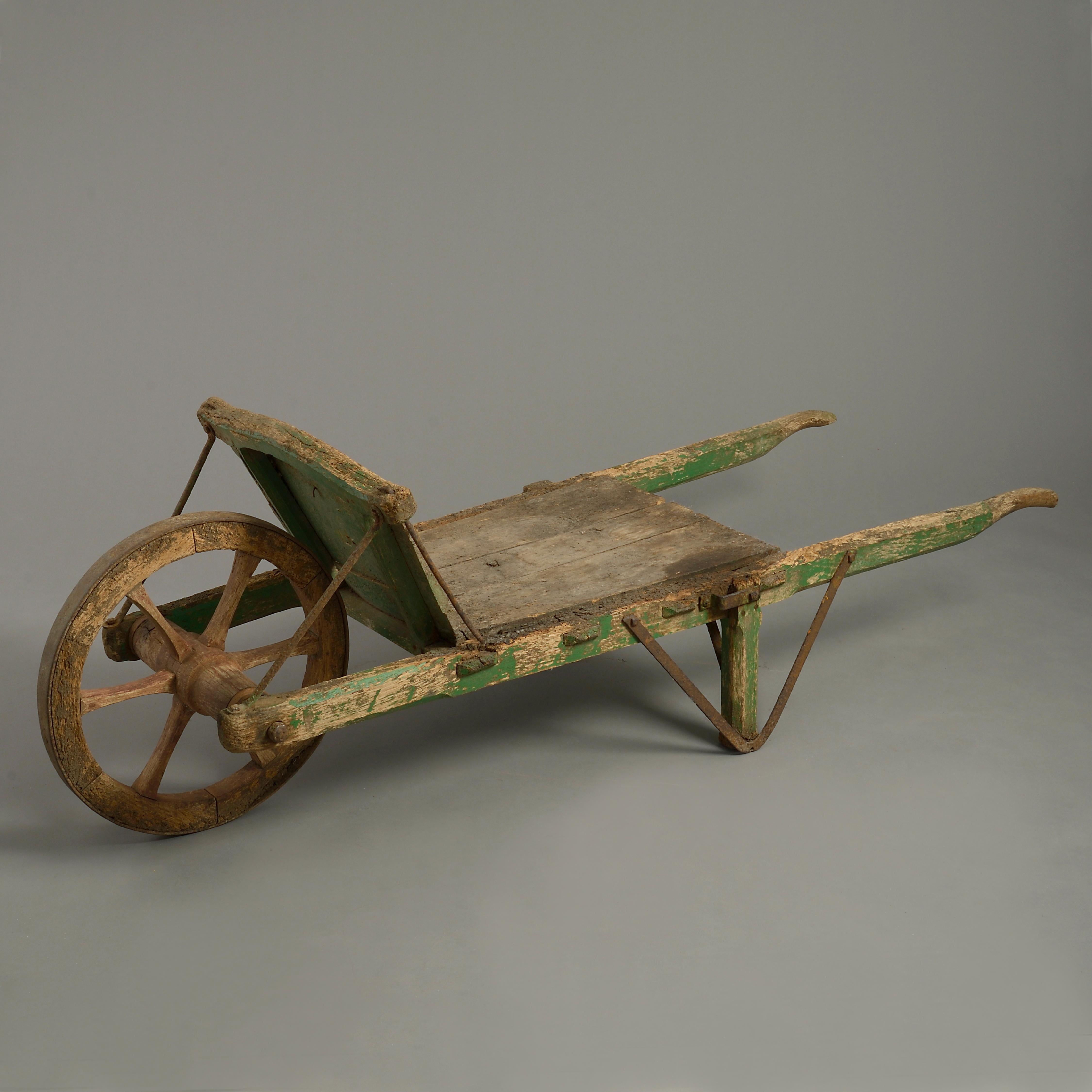 A charming large late 19th century Victorian Period wooden wheelbarrow, having iron mounts and traces of the original green paint throughout.