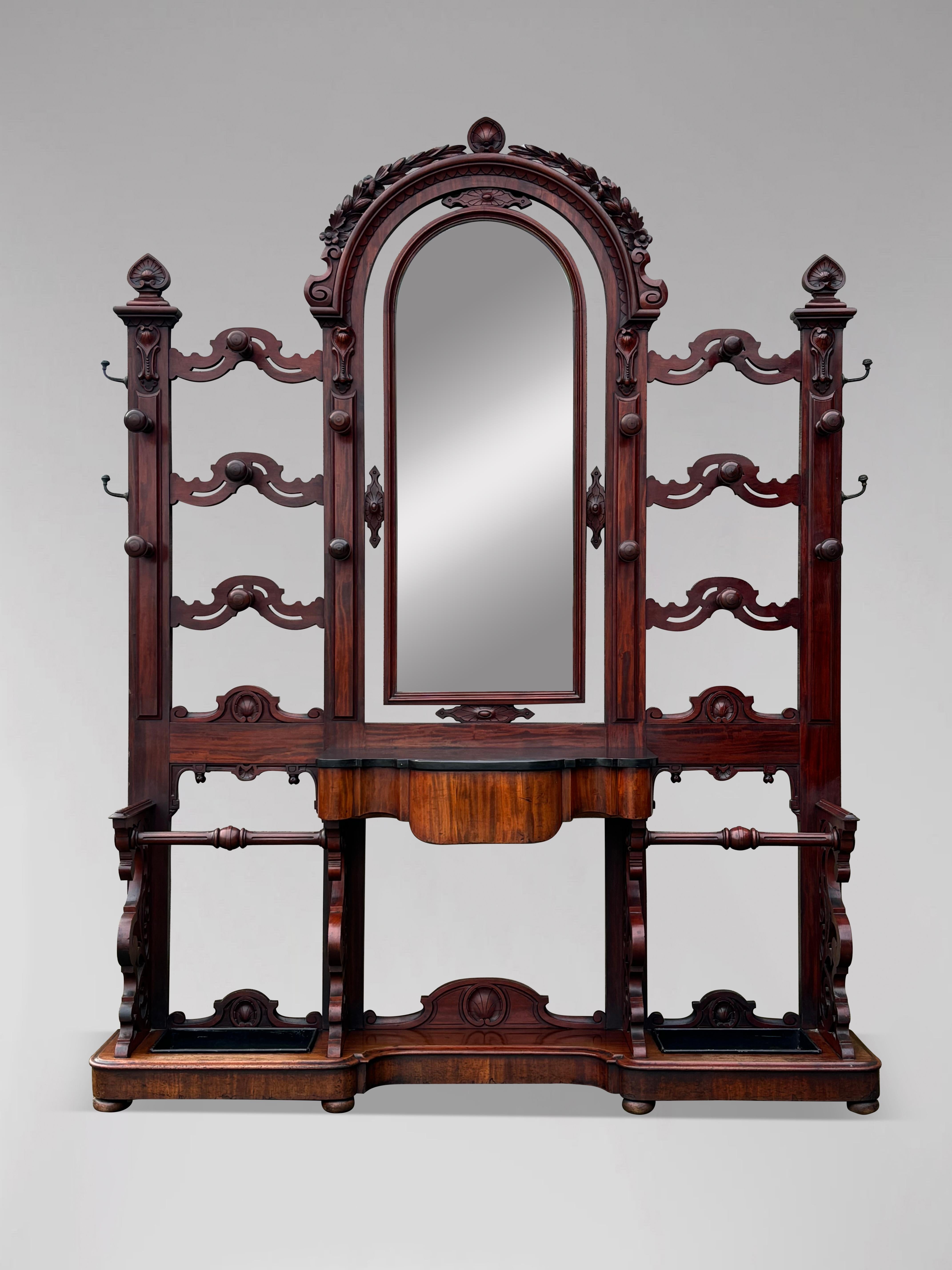 An outstanding 19th century, Victorian period hall stand in solid mahogany with big arched frame, carved detailing, the original marble, 14 original turned mahogany hat and coat supports, 4 brass hooks to the sides and the original centralised