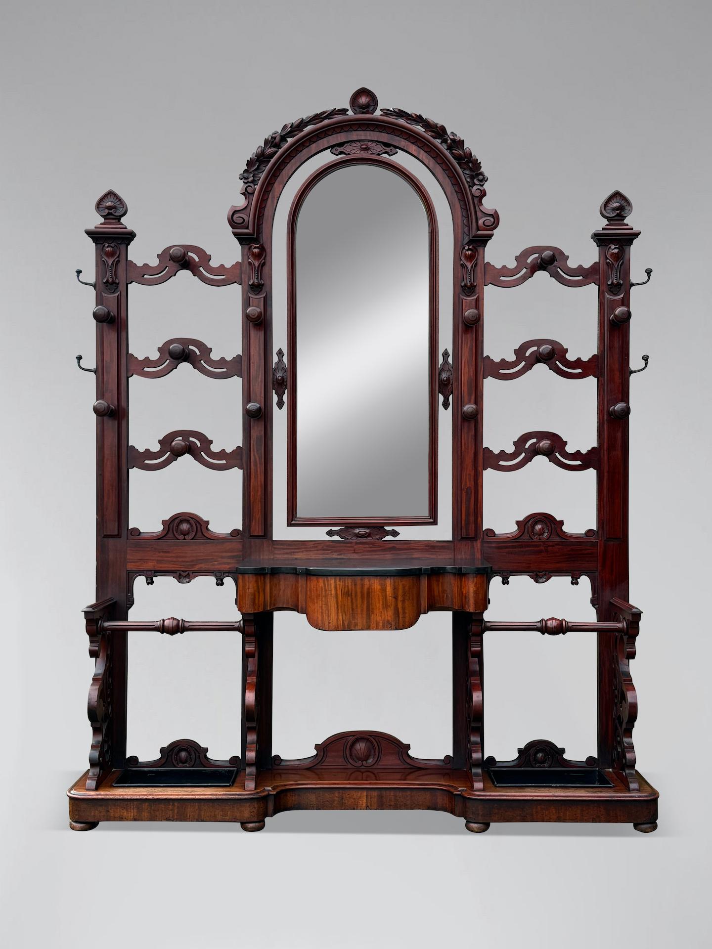 Un'eccezionale piantana d'epoca vittoriana del XIX secolo in mogano massiccio con una grande cornice ad arco e dettagli intagliati. Presenta il marmo originale, 14 supporti originali per cappelli e cappotti in mogano tornito, 4 ganci in ottone sui
