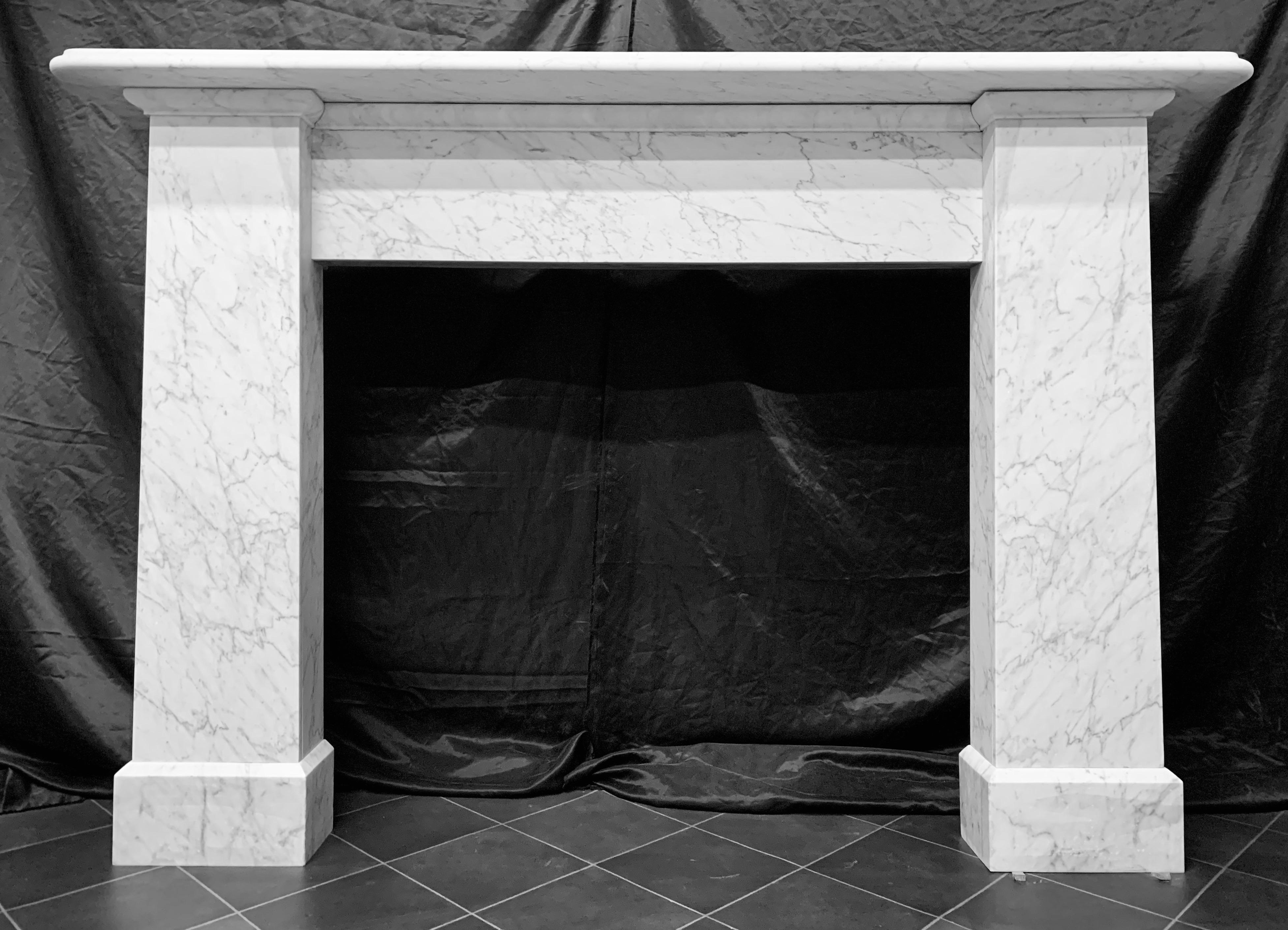 A large and masculine 19th century Scottish Victorian Carrara marble fireplace surround in the Egyptian revival manar, a generous moulded shelf sits above a plain frieze, flanked by tapered bookmatched jambs, capping moulding to the tops of each