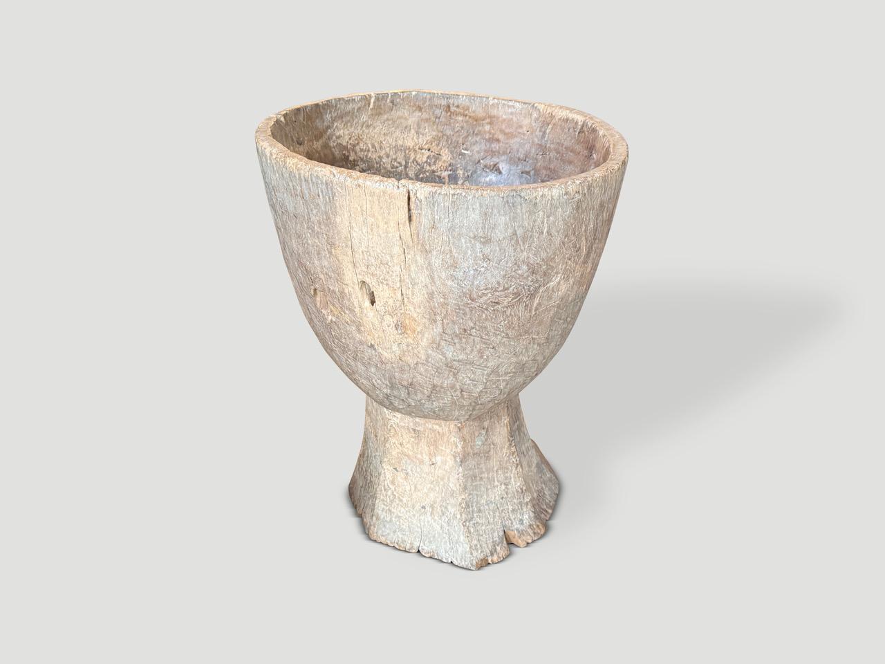Bellissimo mortaio alto antico, originariamente utilizzato per macinare il riso. Scolpito da un unico pezzo di legno di teak. La base smussata intagliata a mano è unica. Dimensioni complete: il piano misura 18