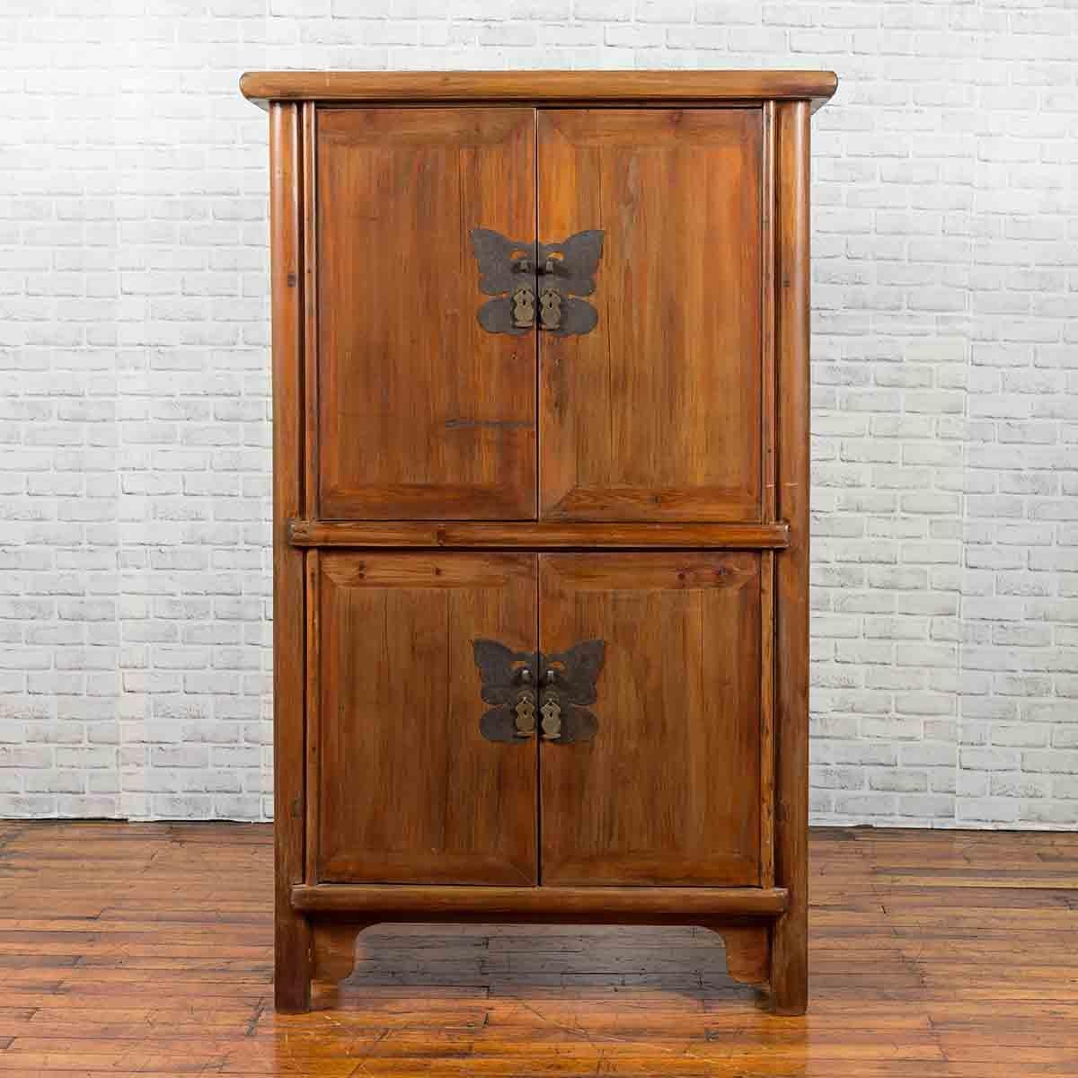 A large wedding cabinet from the 19th century, with two pairs of double doors and large butterfly hardware. This armoire cabinet features two pairs of double doors, each fitted with a cut-out butterfly hardware with etched motifs and fish pulls.
