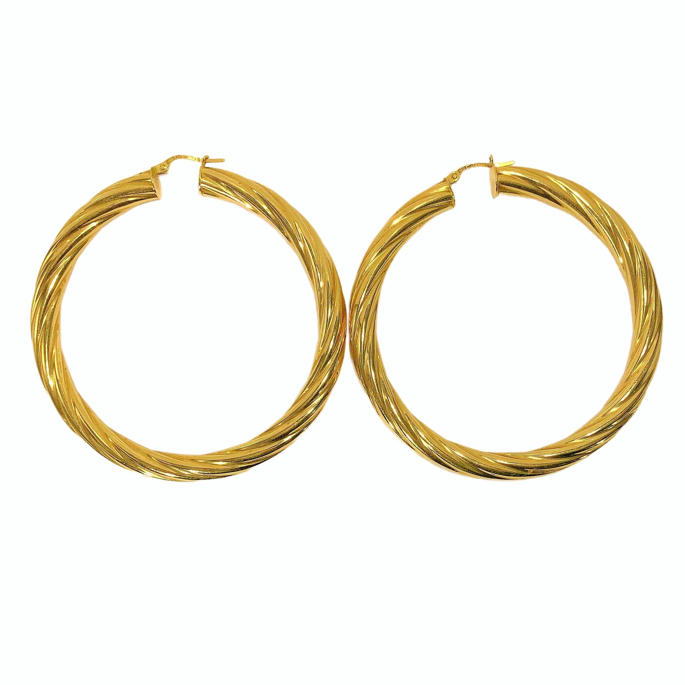 This large and very well made pair of 18K yellow gold Italian twisted and fluted tubular hoop earrings by Unoerre measure a full 2 3/8 inches in outside diameter. With tube diameter of approximately 1/4 inch, this striking pair will not be missed by