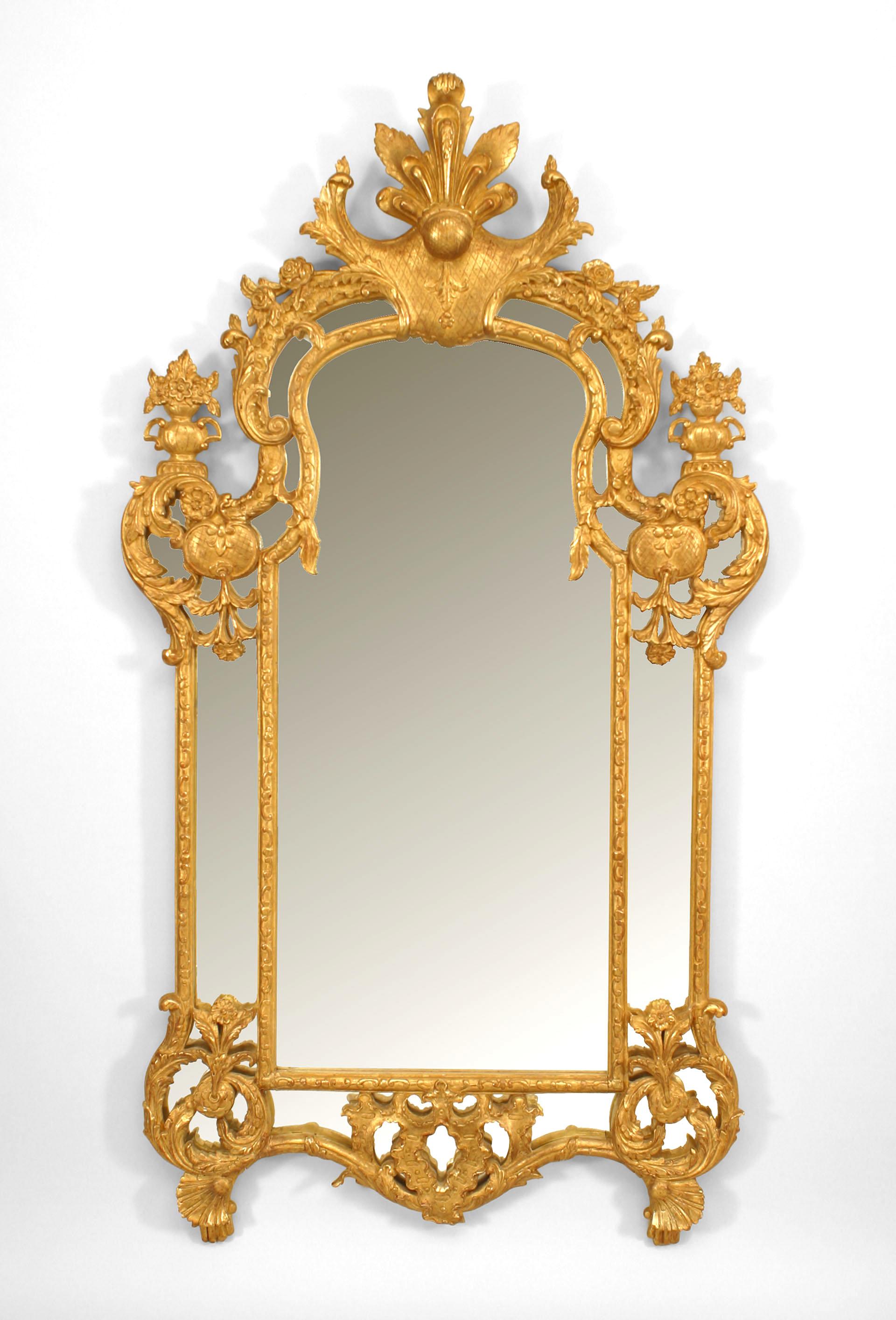 French Regency-style (20th century) gilt vertical wall mirror with carved pediment top and floral and urn design with carved shell design feet.
    