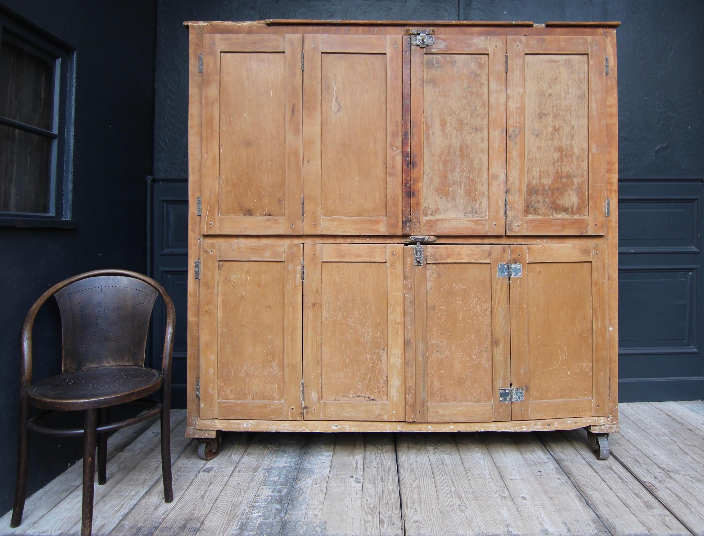 Large vintage bakery cupboard or proofing cupboard from the 1st half of the 20th century. 
Simple rectangular coffered beechwood corpus on industrial iron castors. Behind folding doors are a total of 4 large pull-out shelves made of coniferous wood