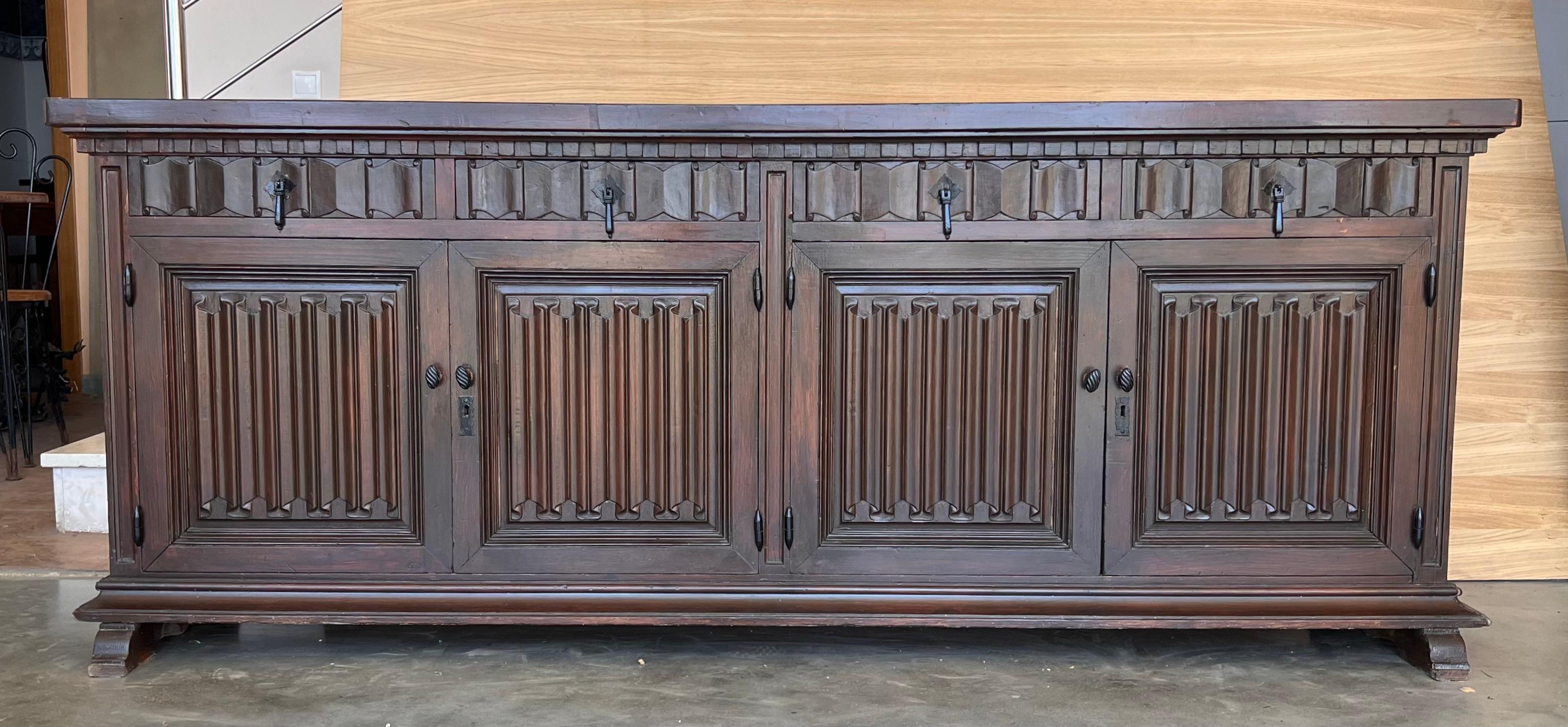 Coming from northern Spain, constructed of solid walnut, the rectangular top with molded edge above a shaped box housing four drawers over four doors, the doors faced with solid walnut and raised on a plinth base. The drawers and doors are hand
