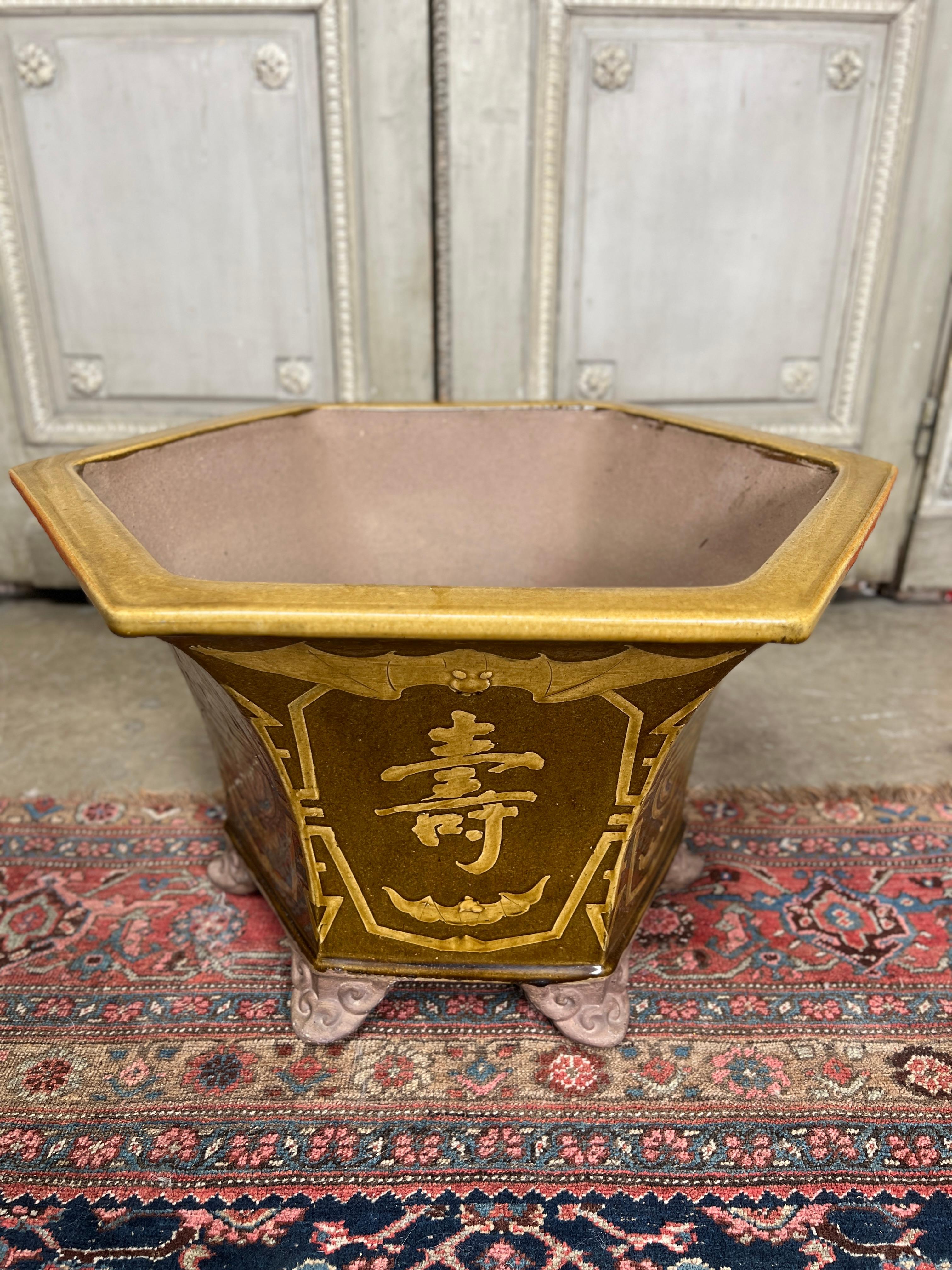 A large Chinese earthenware planter jardiniere with a brown and gold glaze.  
This late 20th century large planter is every decorative and has a bat motif.  