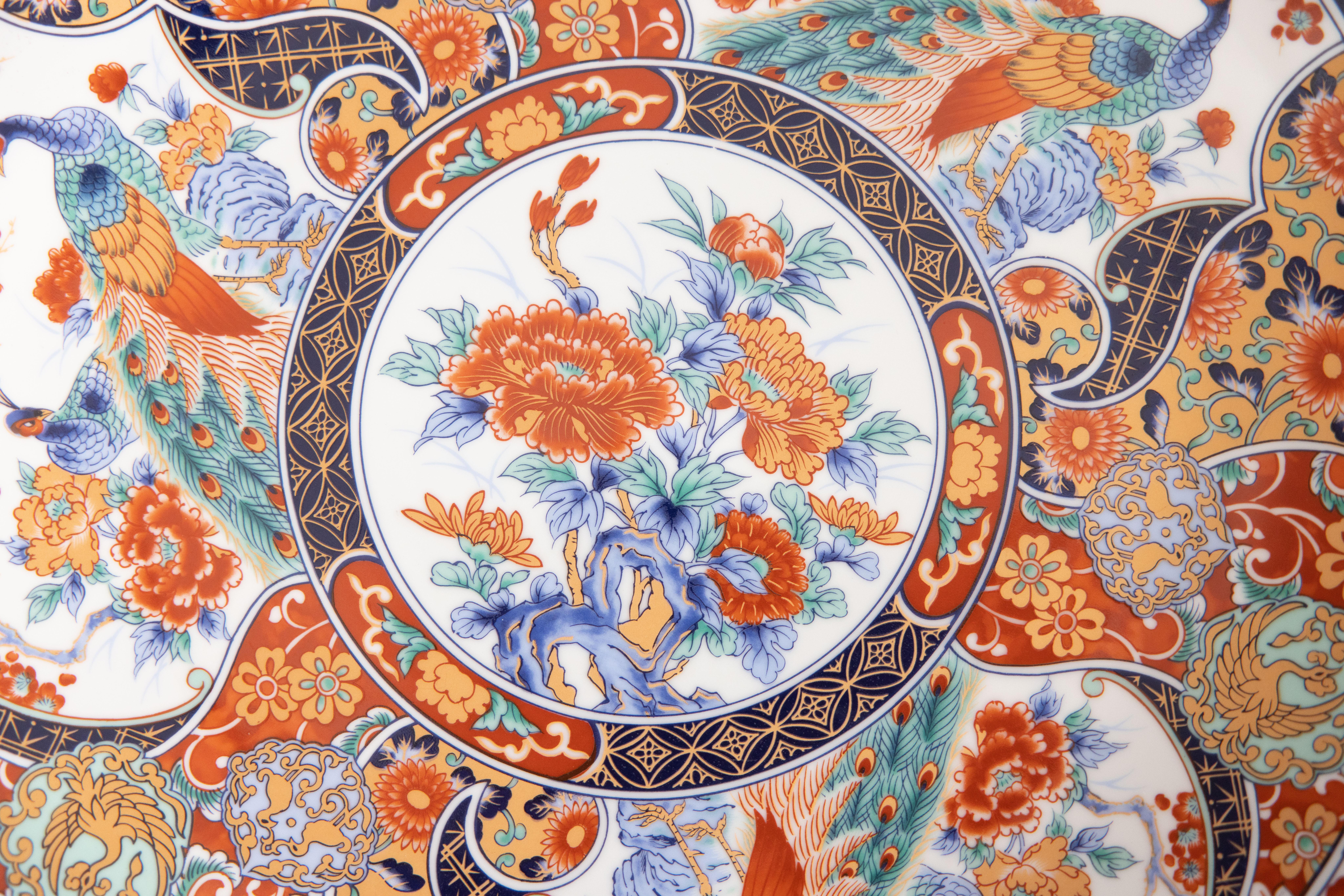 A gorgeous extra large Chinese Imari porcelain charger with a floral design and peacocks in the traditional Imari colors. Marked on underside with four Han characters. This fine large plate has lovely details and is quite heavy, weighing a