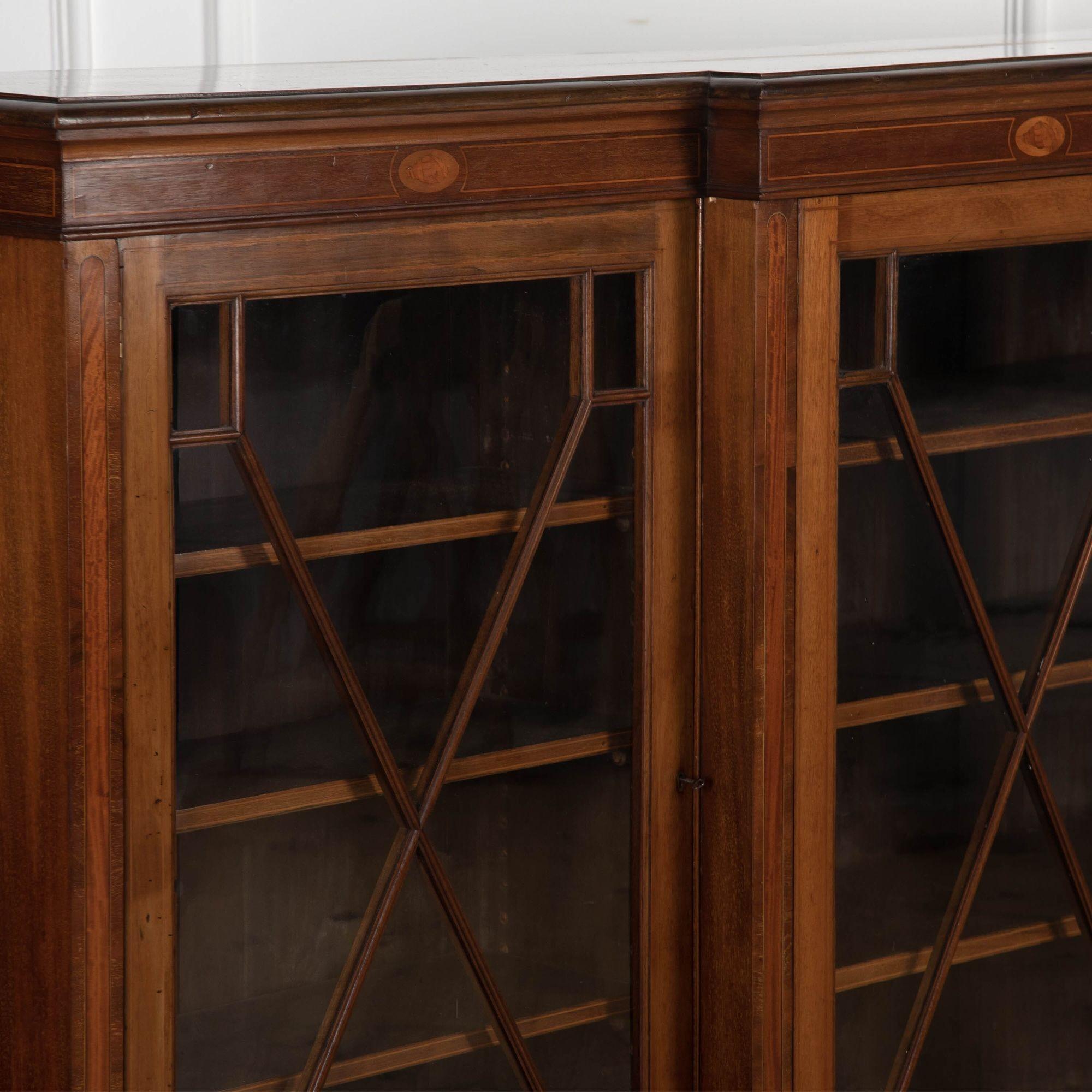 Great early 20th century mahogany and inlaid breakfront bookcase of 9ft proportions.
Of English origin, circa 1910 this four-door glazed bookcase opens to reveal three fully adjustable shelves in each section.
This piece has been cleaned and