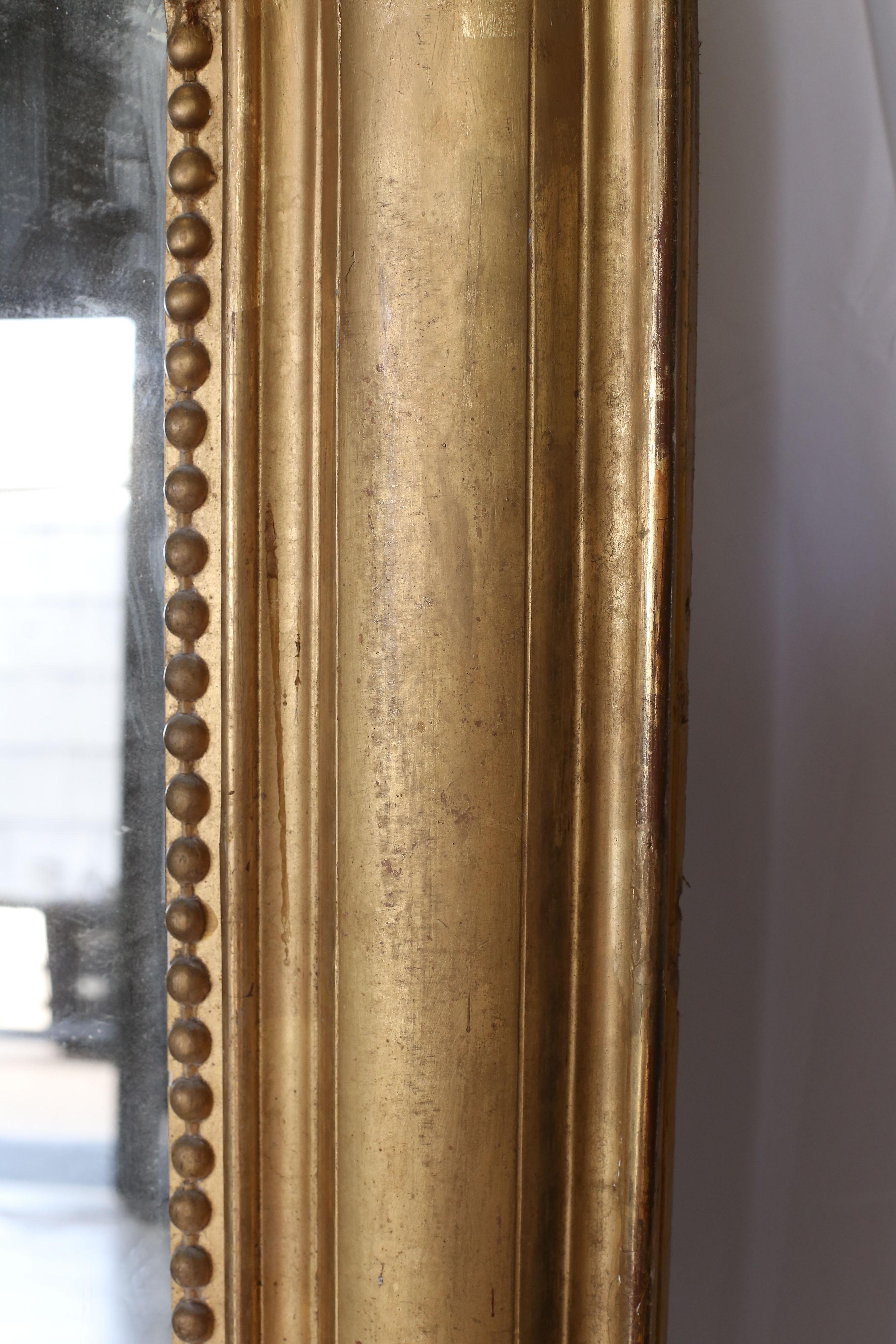 Large 20th century Louis Philippe style mirror. It appears that this mirror was originally made in a brown finish and has had a gilt/gold finish applied to the exterior. The structure is solid but it was not represented correctly upon purchase.