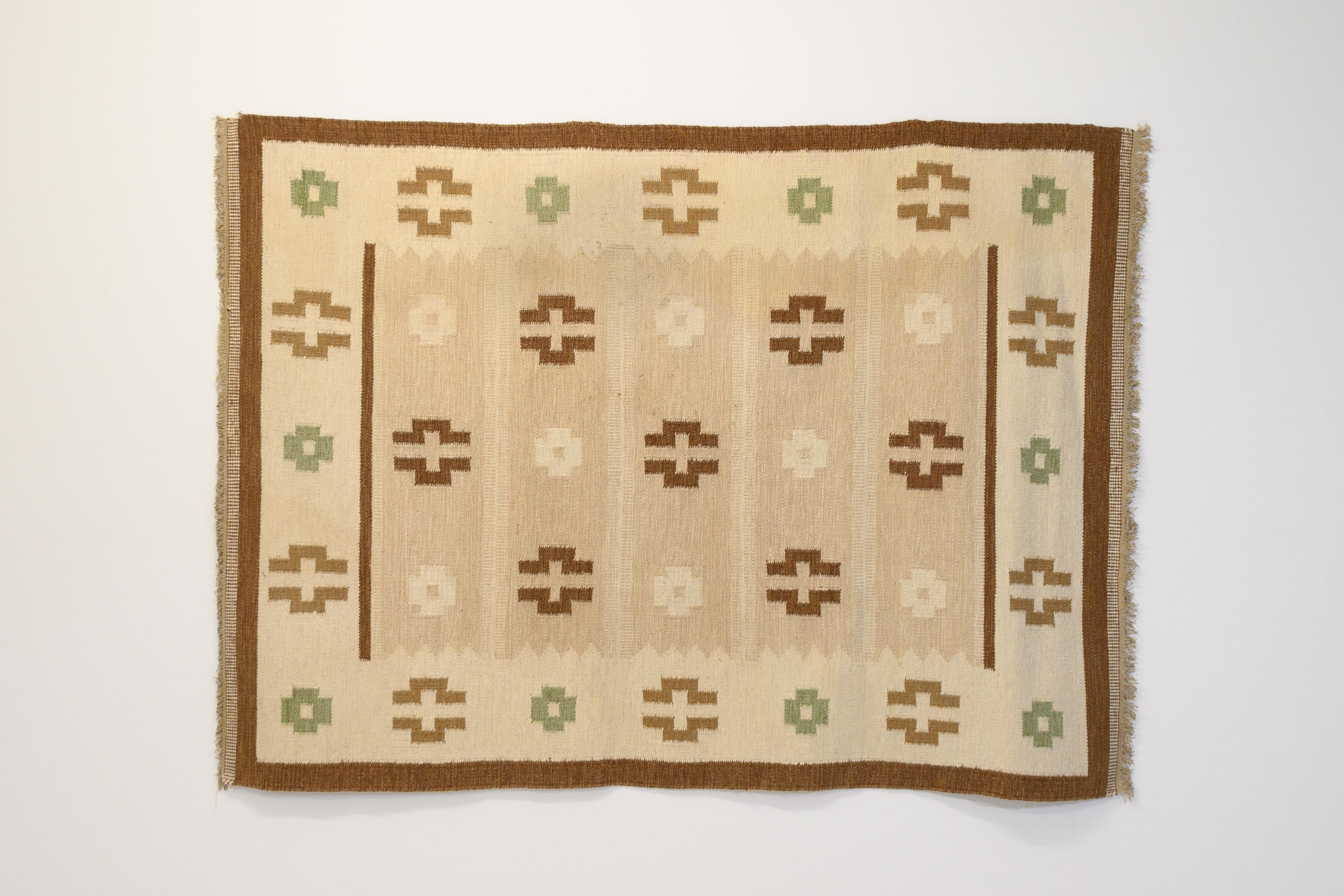 Large mid-century Swedish Kilim in tones of browns and creams decorated with medallions with hints of green and bordered in dark brown. Professionally cleaned.