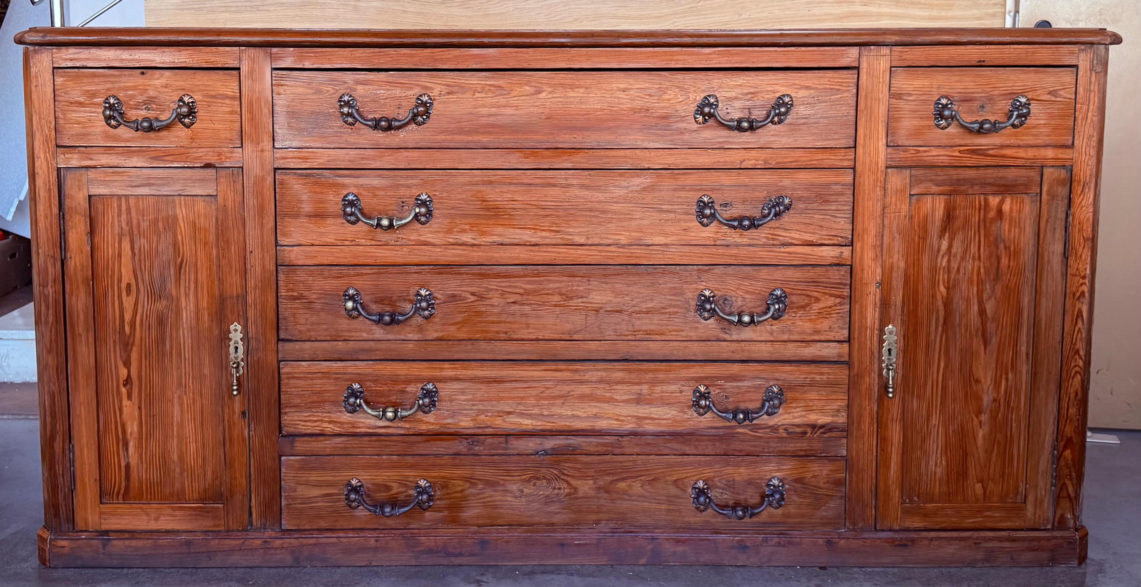 Coming from northern Spain, of an antique Church, this awesome church console was constructed of solid walnut, the rectangular top with molded edge above a shaped box housing seven drawers over two doors, the doors faced with solid walnut and raised