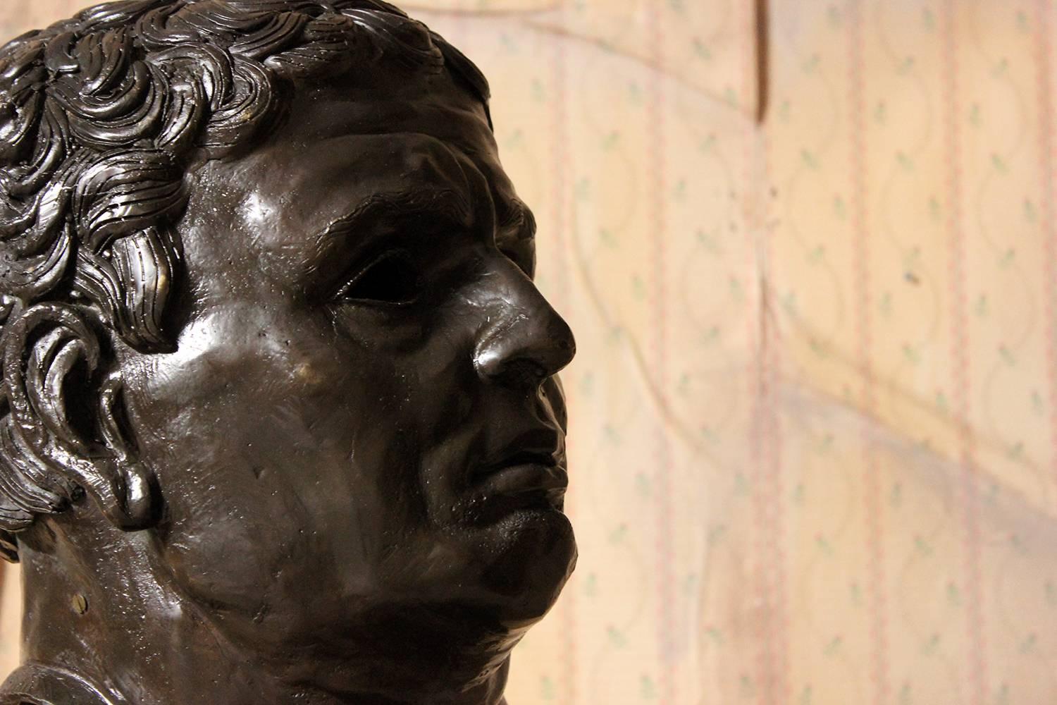 The large and imposing dark patinated bronze portrait bust of a Roman Republican, modeled as a middle aged and fleshy Roman man, with thick tousled hair, the whole on a steel rod and stepped black marble base, surviving from the twentieth