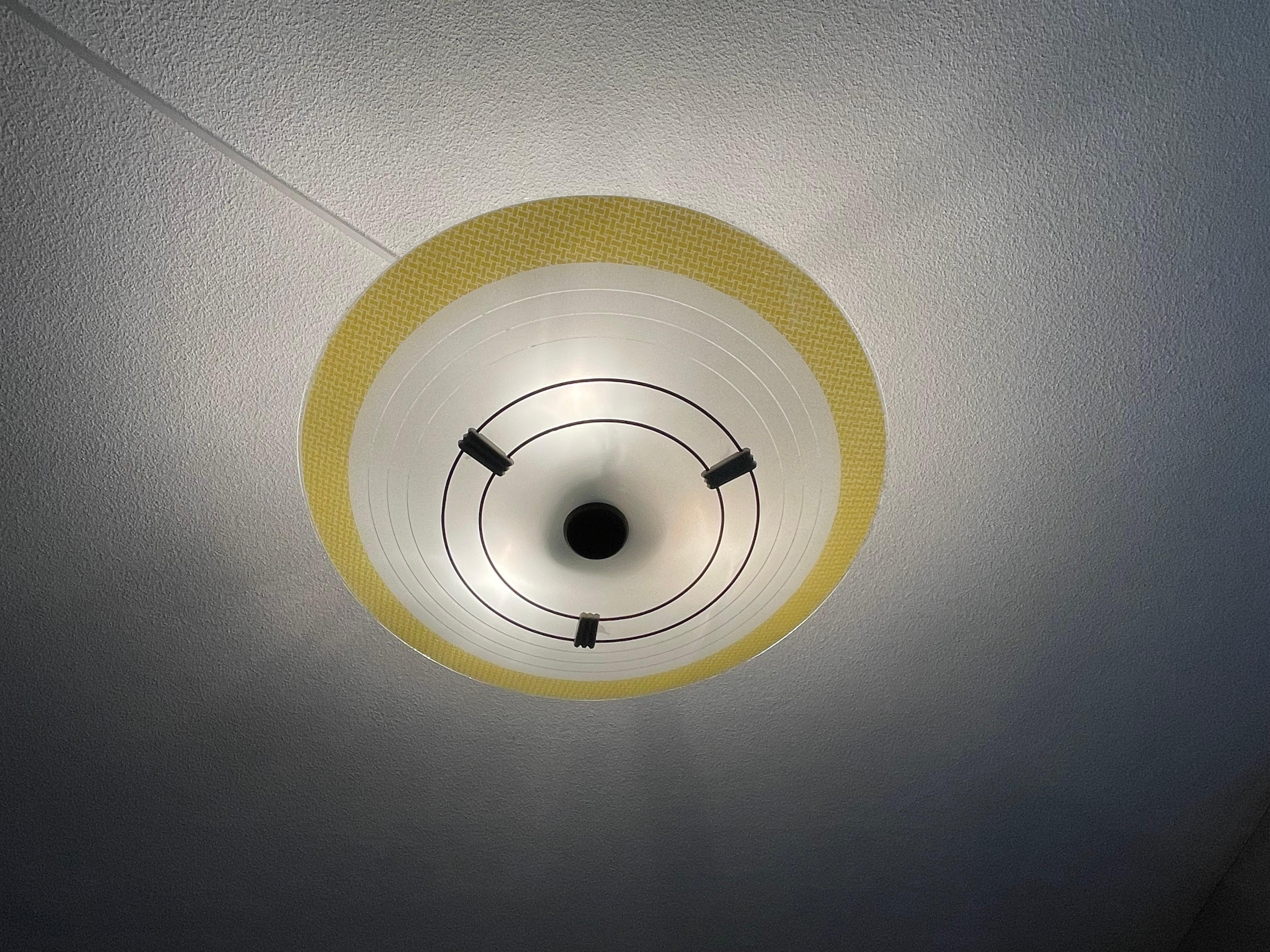 Very stylish Mid-Century Modern, yellow, white and black circular design ceiling lamp.

This vintage light fixture has a beautiful look and feel and you will hardly ever find a light fixture from the Mid-Century Modern era with a more timeless glass