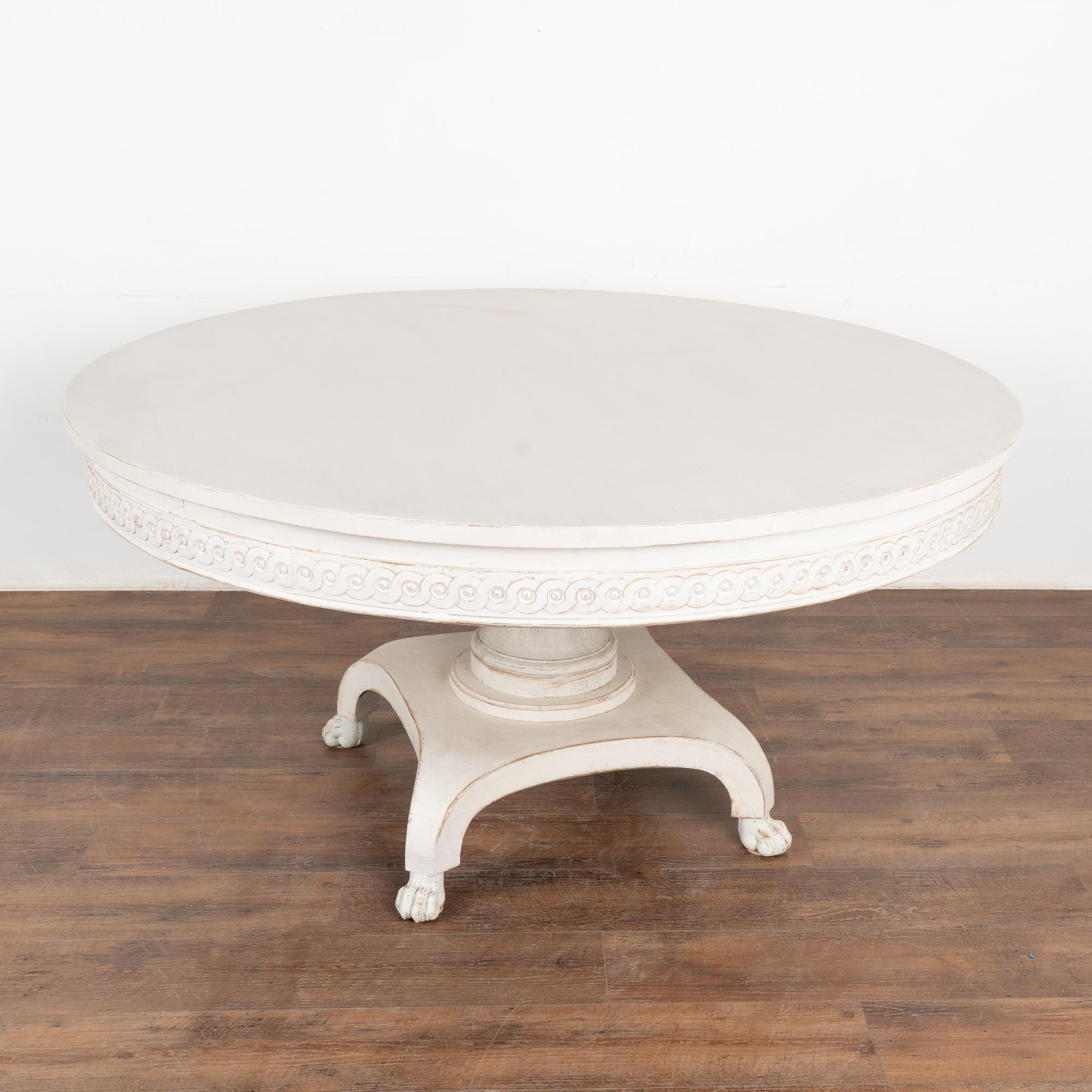 This large round pedestal 5' table has a decorative carved skirt and dramatic pedestal base resting on four carved lion's paw feet.
Restored, later professionally painted in white and lightly distressed to fit the age and grace of this impressive
