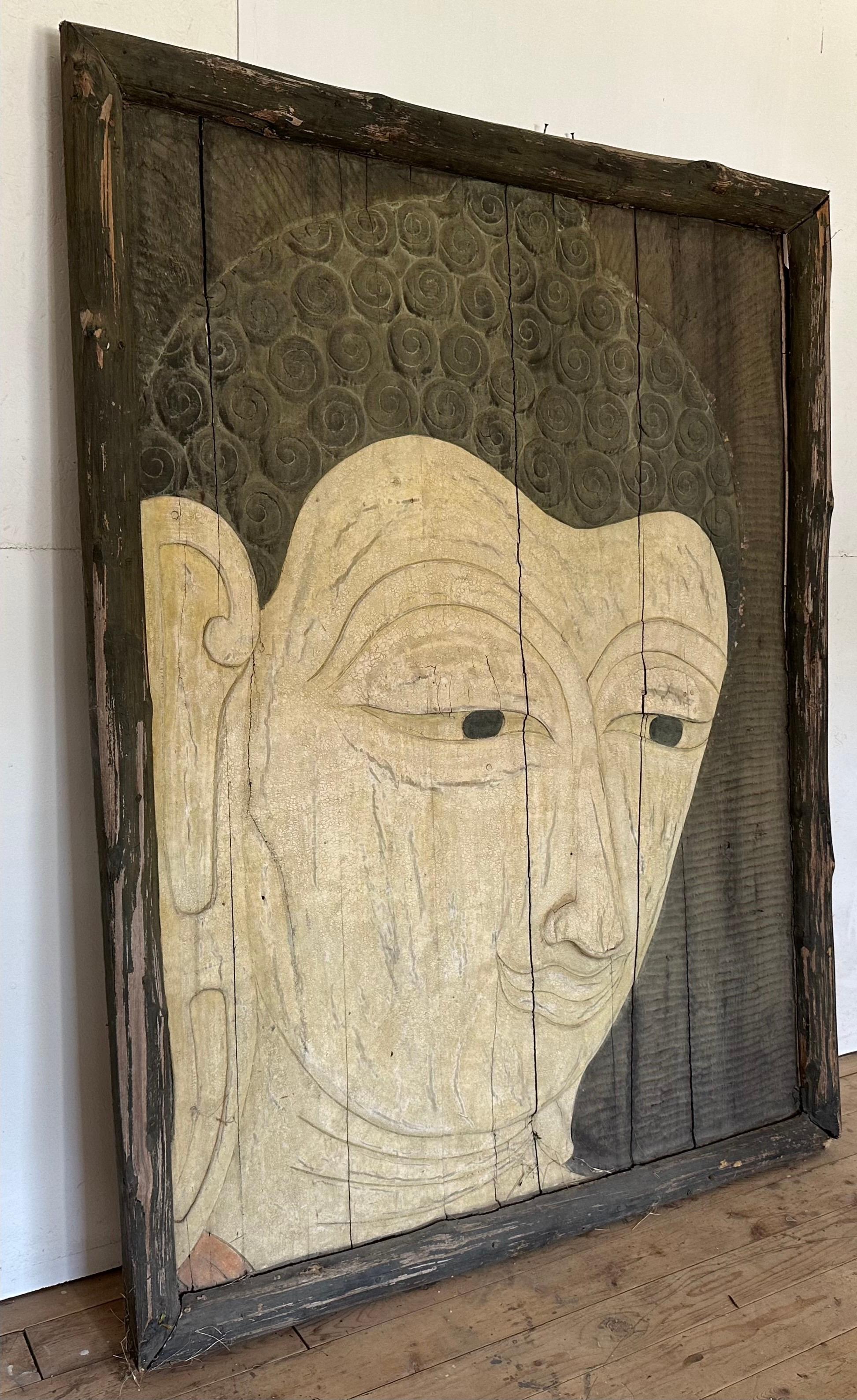A very large and most impressive carved wood relief of a head of a Buddha. The stunning sculpture has interesting details. The panel once hung in the lobby of a hotel in Japan. A piece can stand on the floor or be hung on a wall. Measures: 5'X7'.