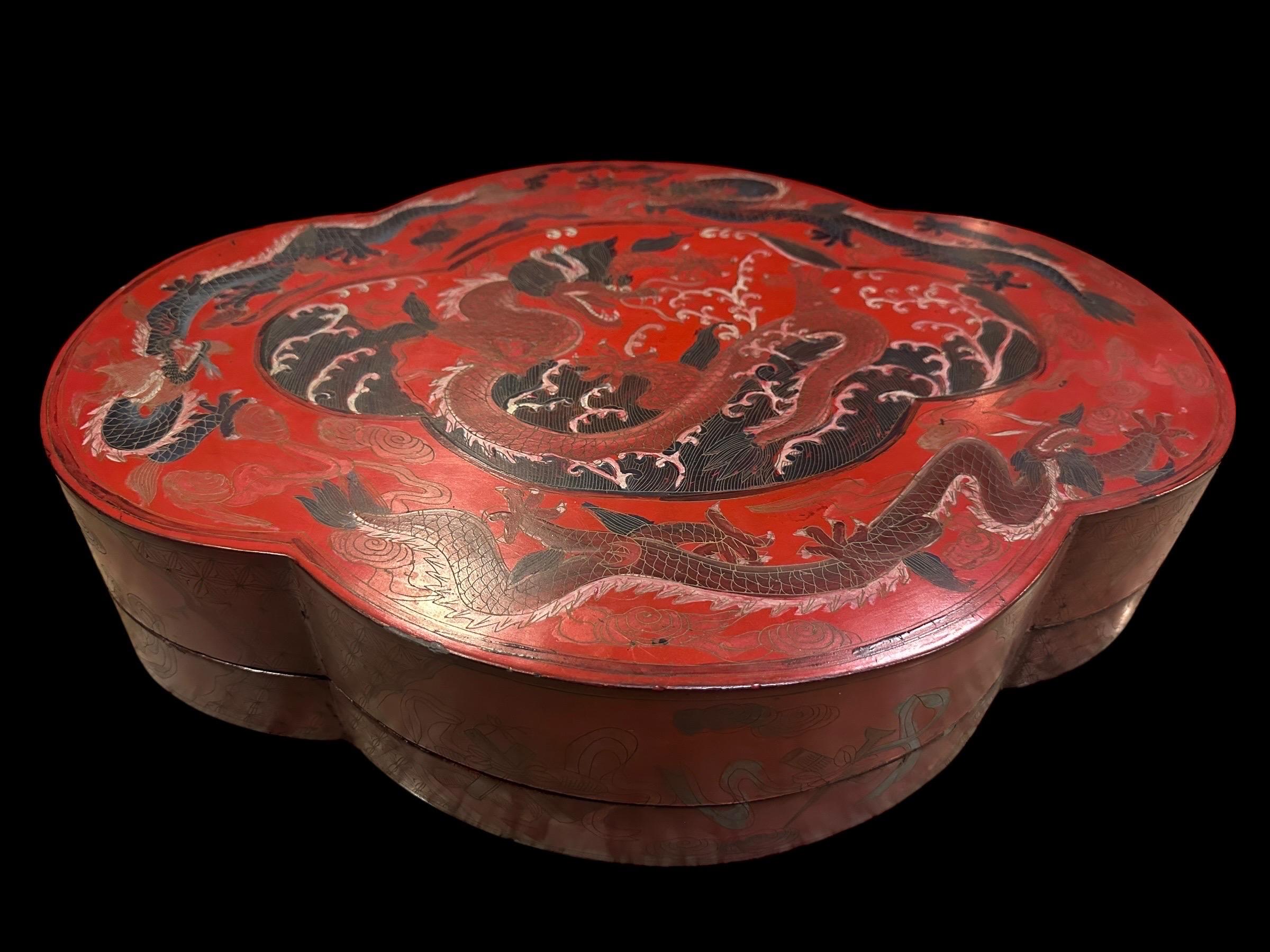 Il s'agit d'une grande boîte de rangement lobée en laque rouge chinoise de 50 cm, probablement ornée de motifs complexes. La boîte est décorée à la main de sgraffites, mettant en valeur un dragon impérial à trois griffes sur le couvercle,