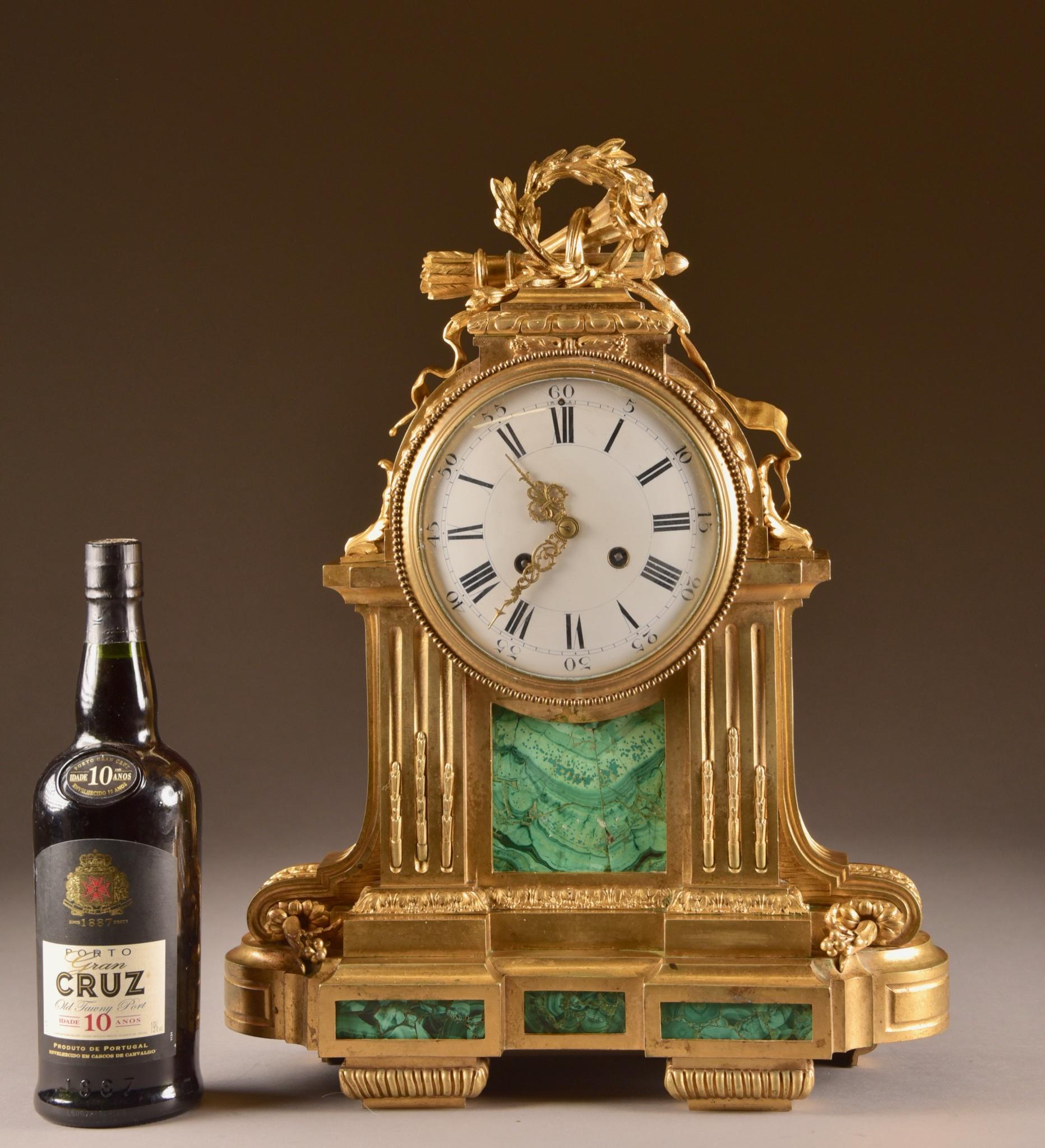A large 18th-early 19th century French fire gilt bronze with malachite pendulum in neoclassical style. Awarded with a torch, quiver and wreath and enamel dial.

This clock comes with a key and a pendulum. Clockwork has recently been checked and