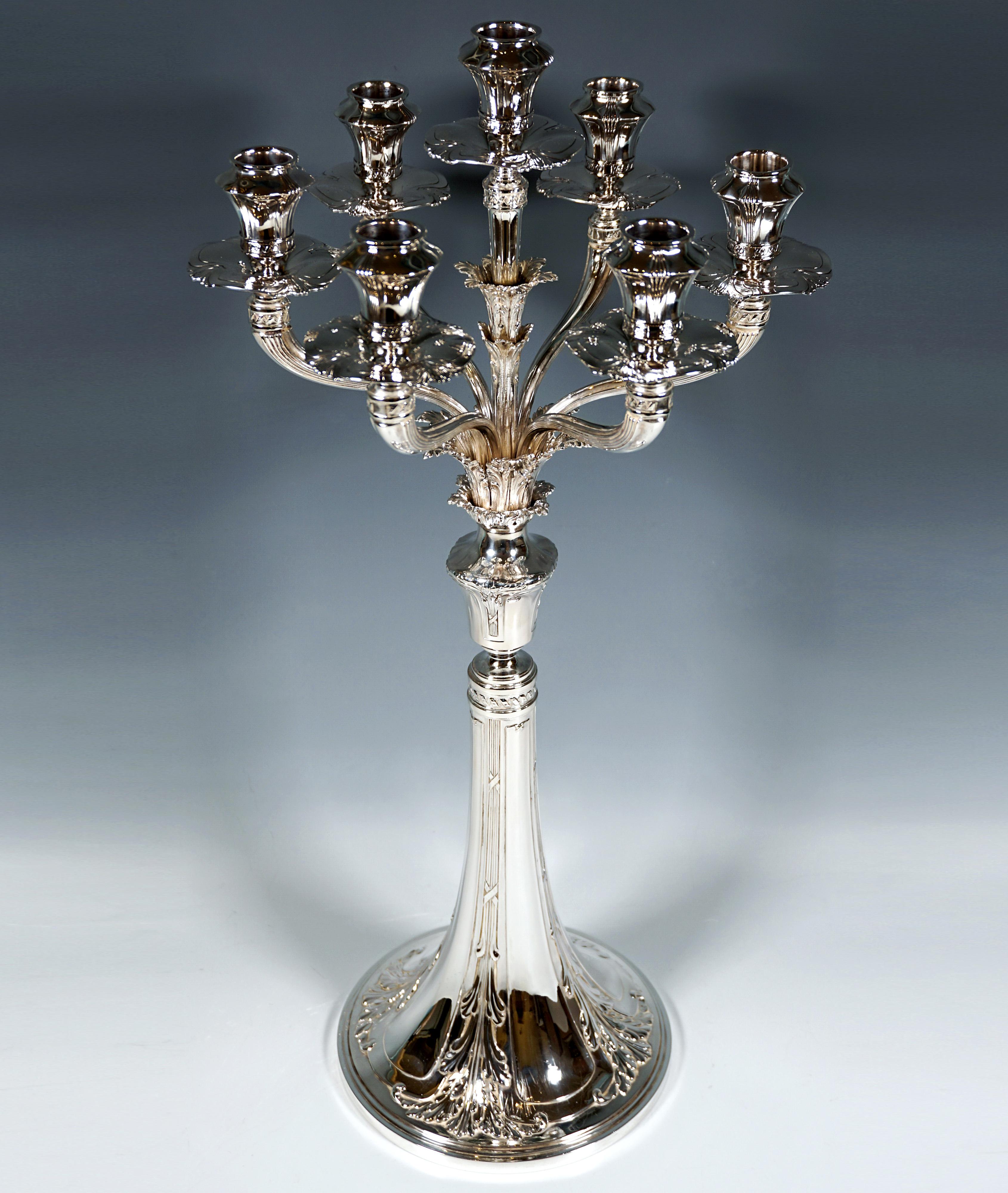 Seven-flame silver candelabra on a round, trumpet-shaped raised foot, divided into eight sections with a relief decoration of bundled cross bands and acanthus leaves, baluster-shaped knot piece with an attached chalice with a double-shaped acanthus