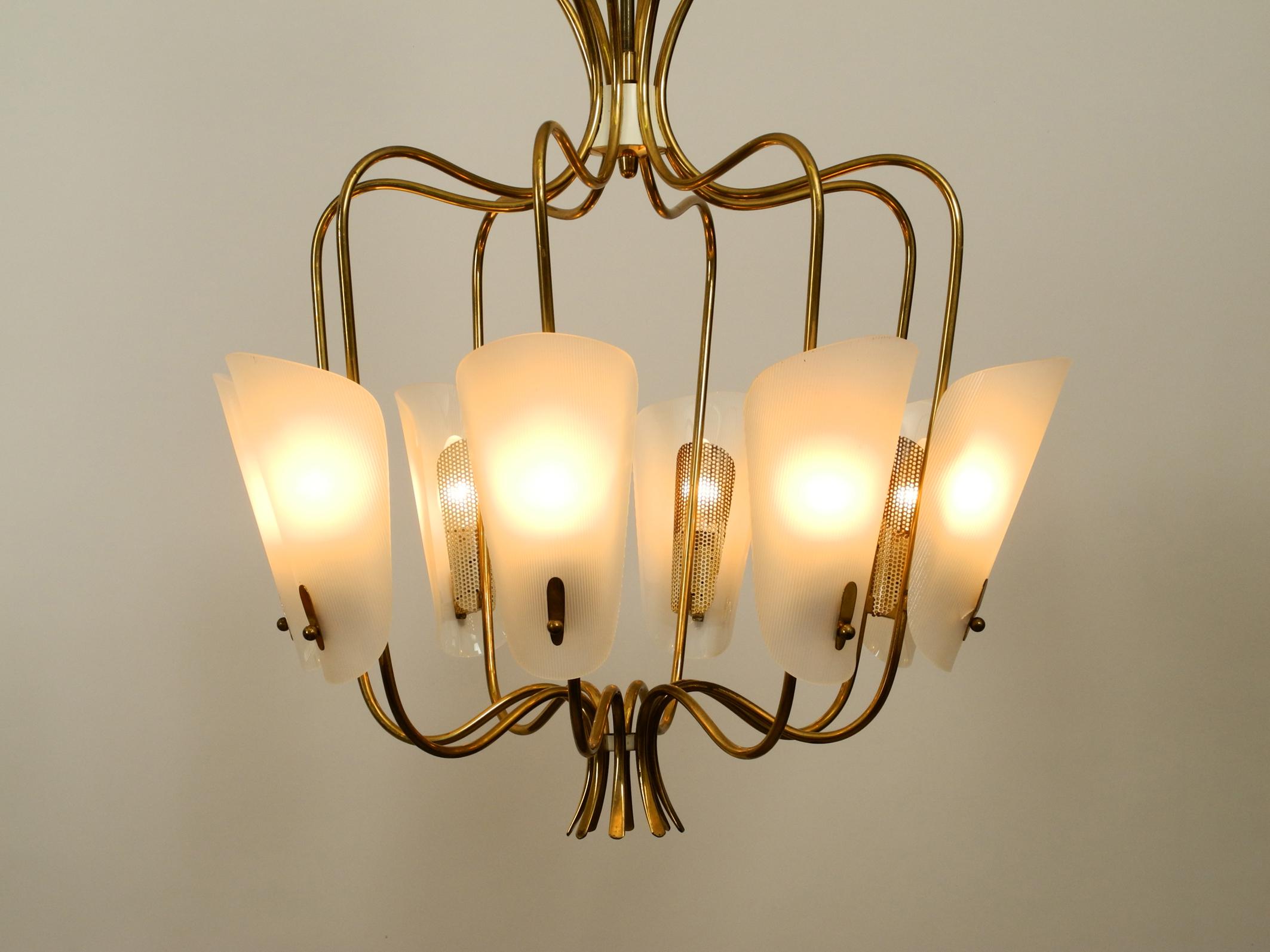 Gorgeous large Mid-Century Modern brass chandelier with
eight curved brass arms and large plexiglass shades.
Exceptional rare design from the 1950s.
Eight original metal E14 sockets for max. 40W each.
In very good collector's