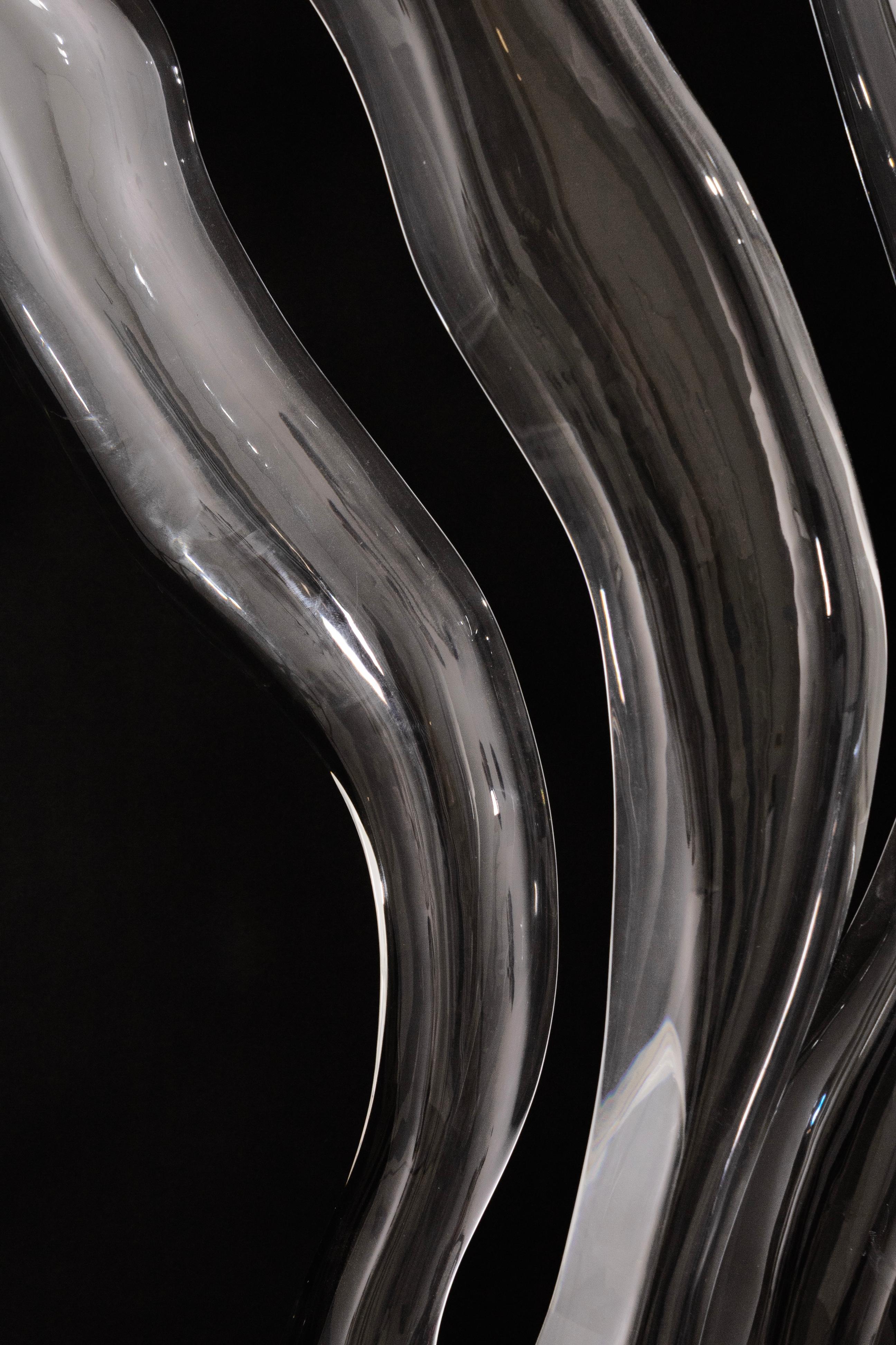 A striking large-scale abstract floor sculpture signed by Phelps, crafted from clear Lucite with fluid, organic wave-like forms rising from a circular base. Its smooth, transparent design captures and reflects light beautifully, creating a sense of