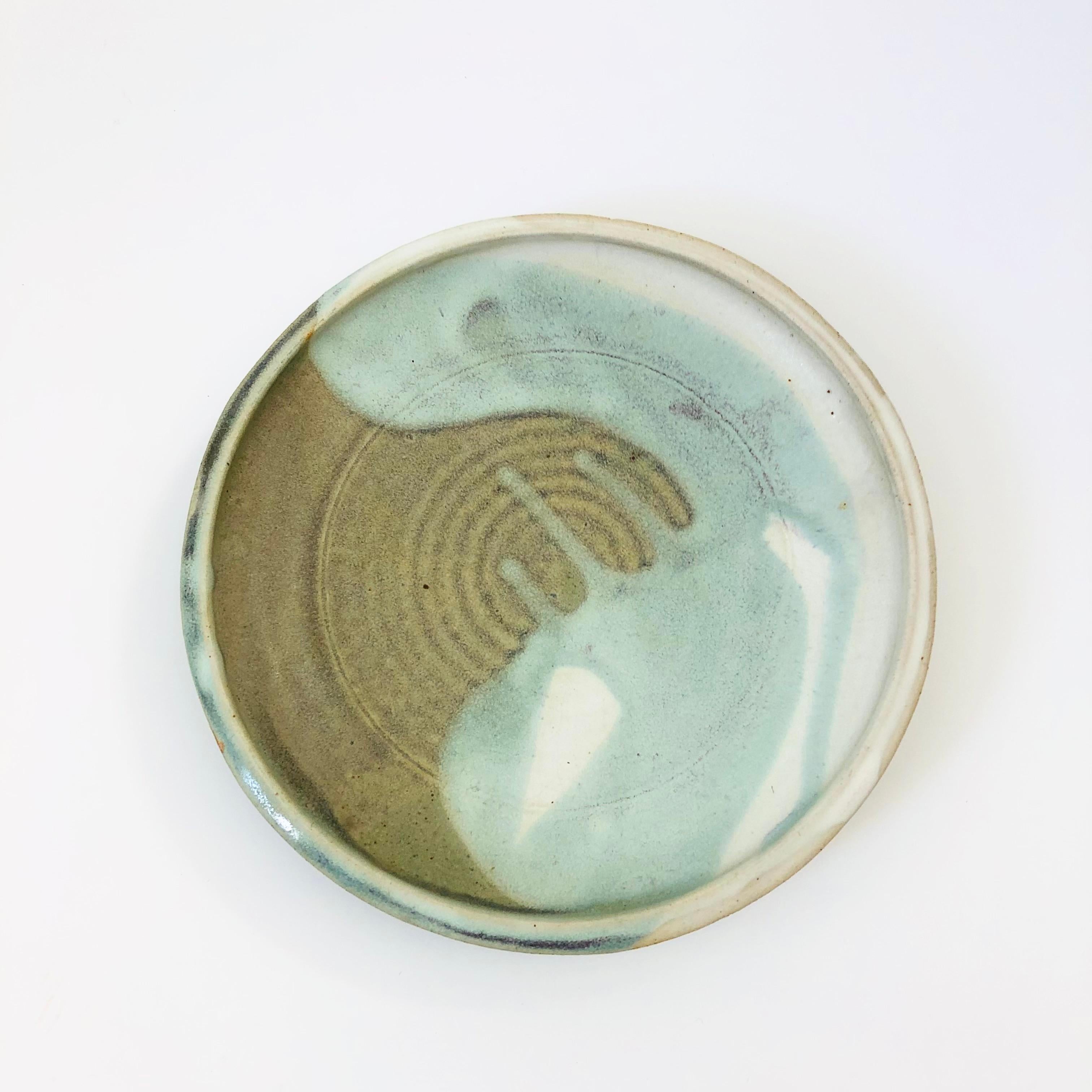 A large vintage circular studio pottery tray. Muted green glazes in an abstract design. Signed on the base 