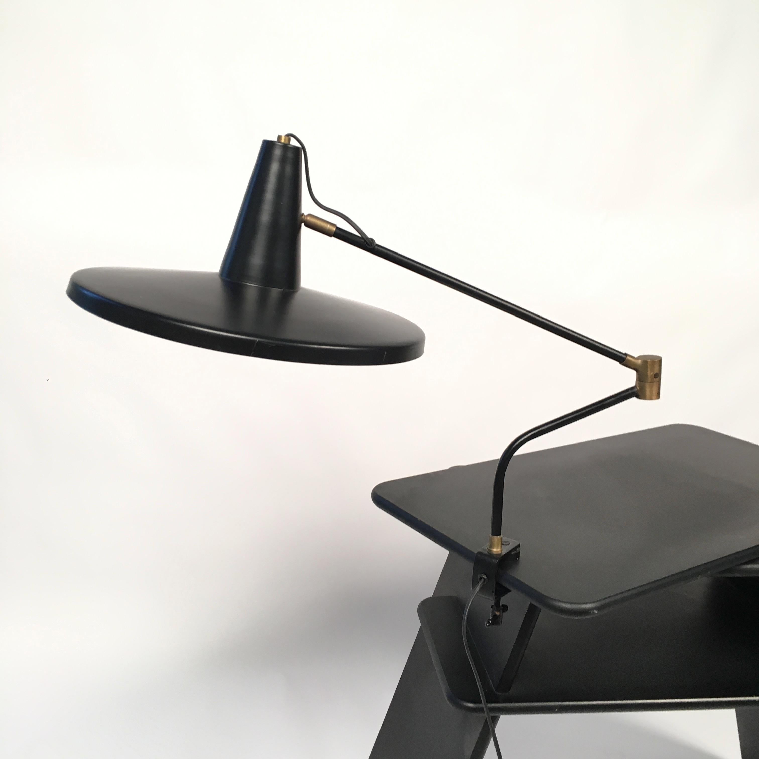 Adjustable articulated desk lamp in Stilnovo style, in black metal and brass.

Dimensions: shorter arm 22 cm; longer arm 46 cm; cup diameter 39 cm.