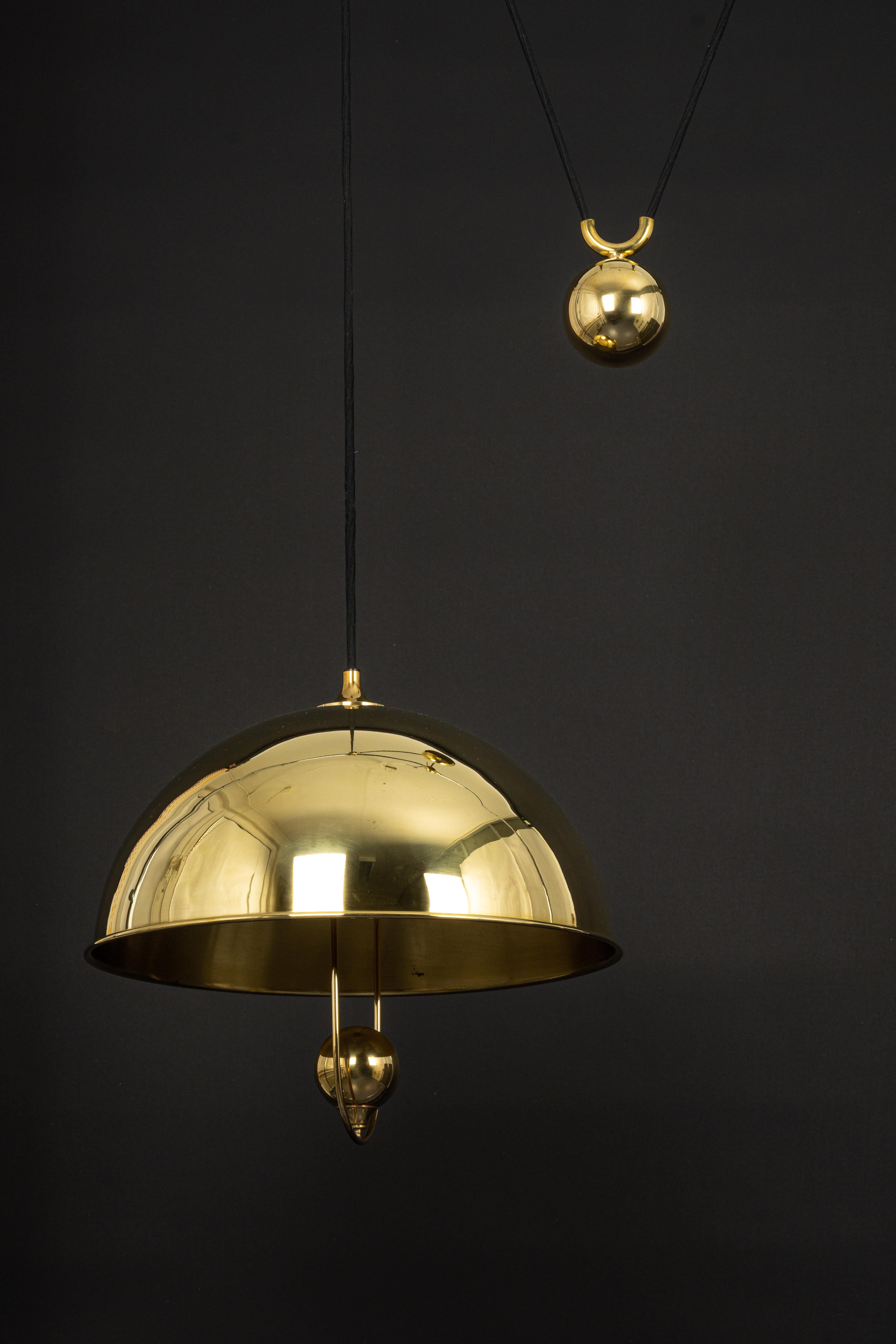 Stunning brass pendant with adjustable counterweight designed by Florian Schulz, Germany, 1970s

One heavy metal ball counterweight and one brass dome. Cloth cord.
Good vintage condition, with small signs of age and use. Height is