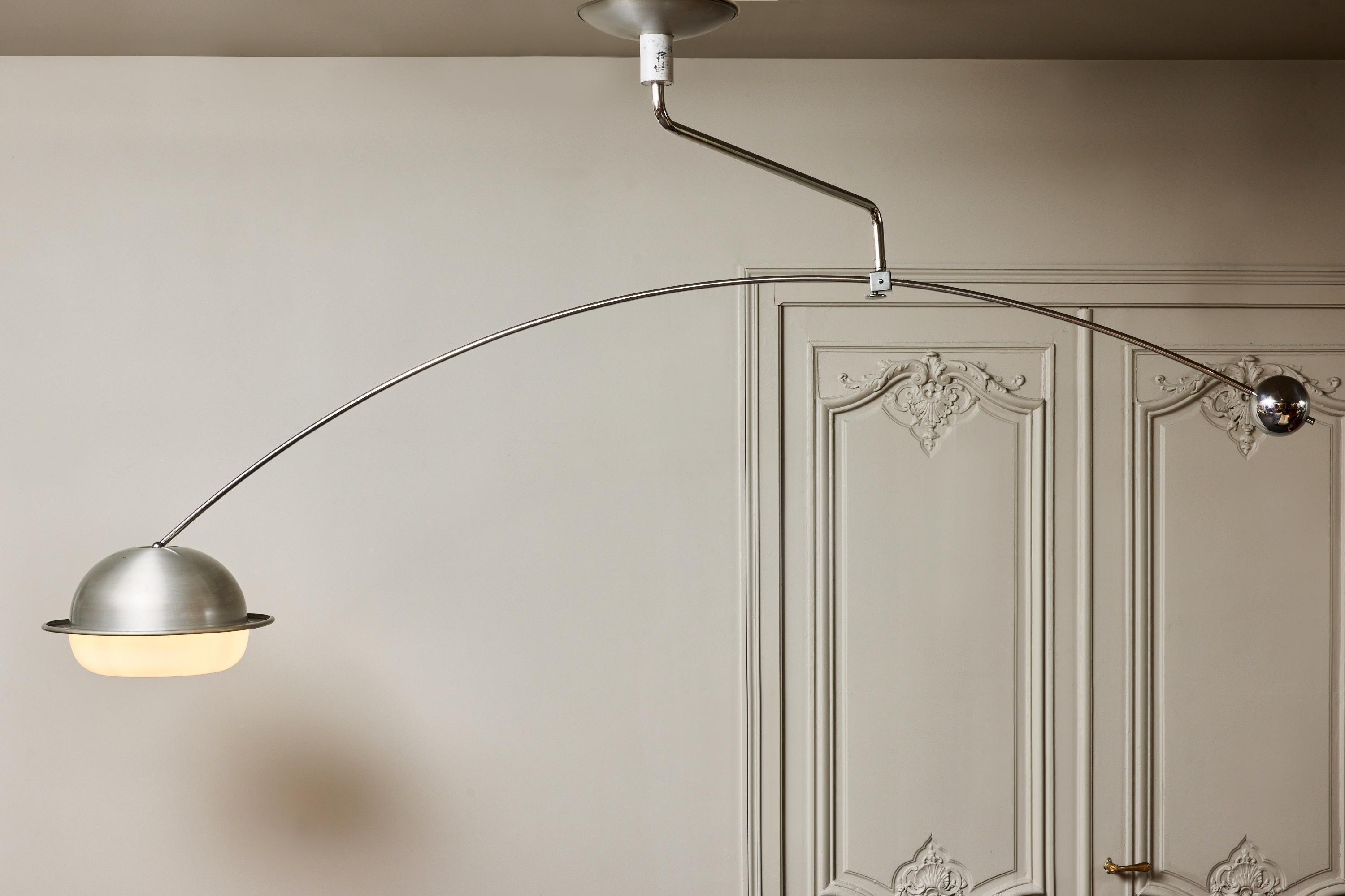 A striking and rare adjustable counterbalance ceiling lamp by Filvem Voghera, crafted in Italy in the 1970s. 
The lamp features a long arched chromed-steel arm balanced by a polished spherical counterweight, allowing smooth horizontal positioning