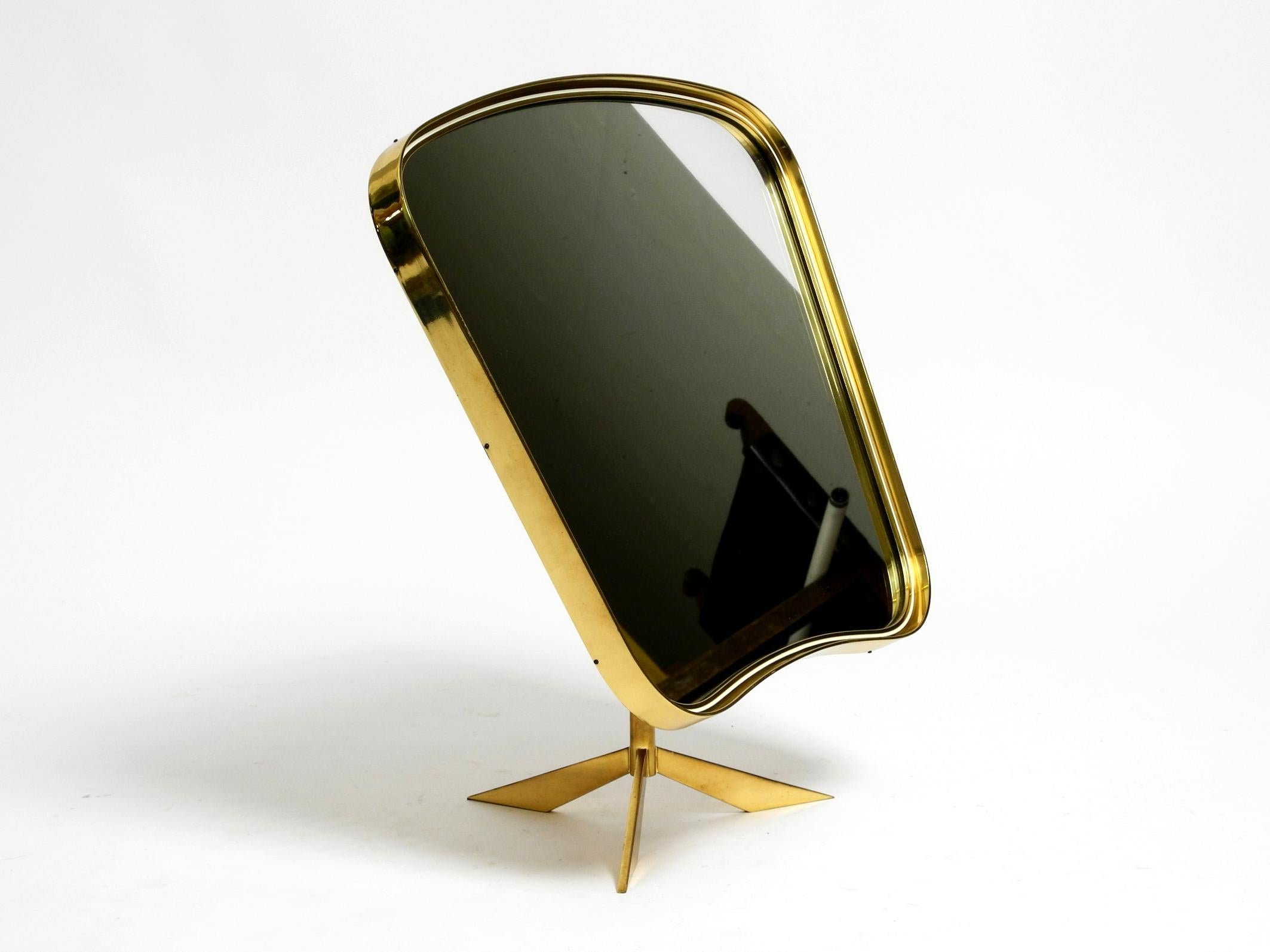 Beautiful, very rare, large, adjustable Mid Century Modern tripod table mirror.
Manufacturer is Vereinigte Werkstätten. Made in Germany.
In the typical 1950s design with a curved brass frame and tripod base.
Entire mirror frame is made of heavy