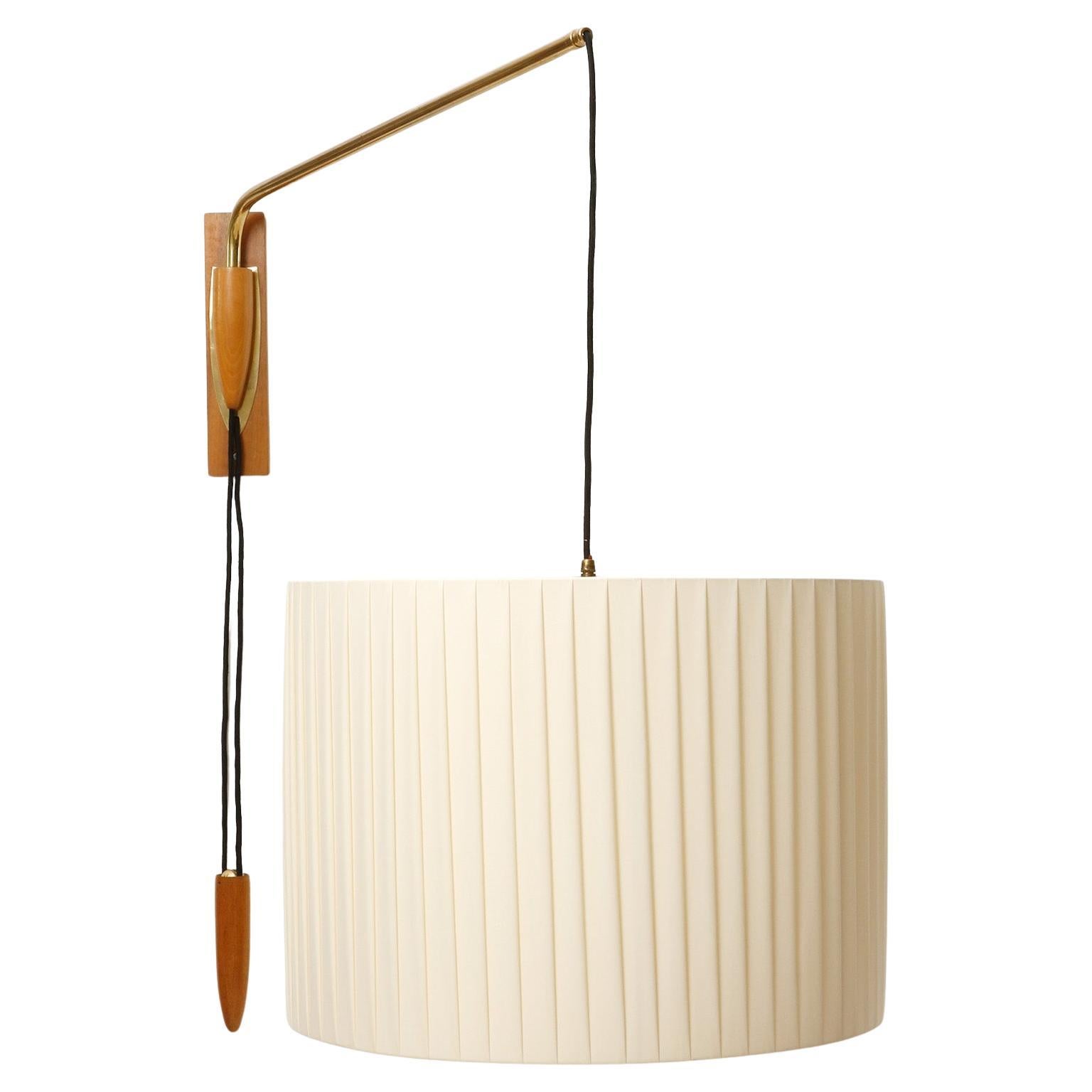 Una fantastica applique in legno e ottone con paralume in tessuto plissettato color crema di Rupert Nikoll, Vienna, Austria, prodotta nel 1960 circa (fine anni '50 o inizio anni '60). T
a posizione del paralume è ajdustbale in altezza con un