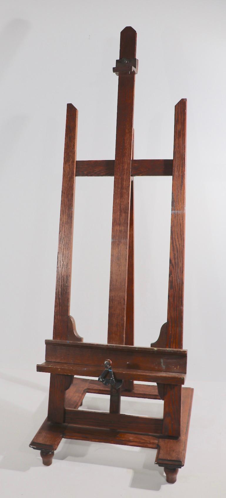 Impressive artists easel constructed of solid oak, with cast brass hinges and a cast iron crank handle. The easel is adjustable, the lower tray can be raised or lowered as can the top clip, the vertical element can be moved forward and back to