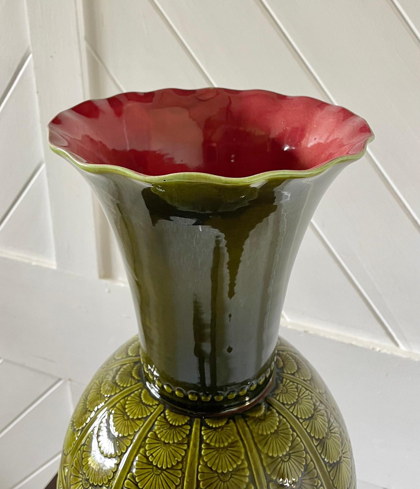 Mouvement esthétique grand vase en poterie émaillée

Vert olive avec intérieur rose et bord cannelé

Les épaules sont festonnées de marguerites.

4 rondeaux centraux représentant des papillons stylisés parmi des feuillages

À la manière de