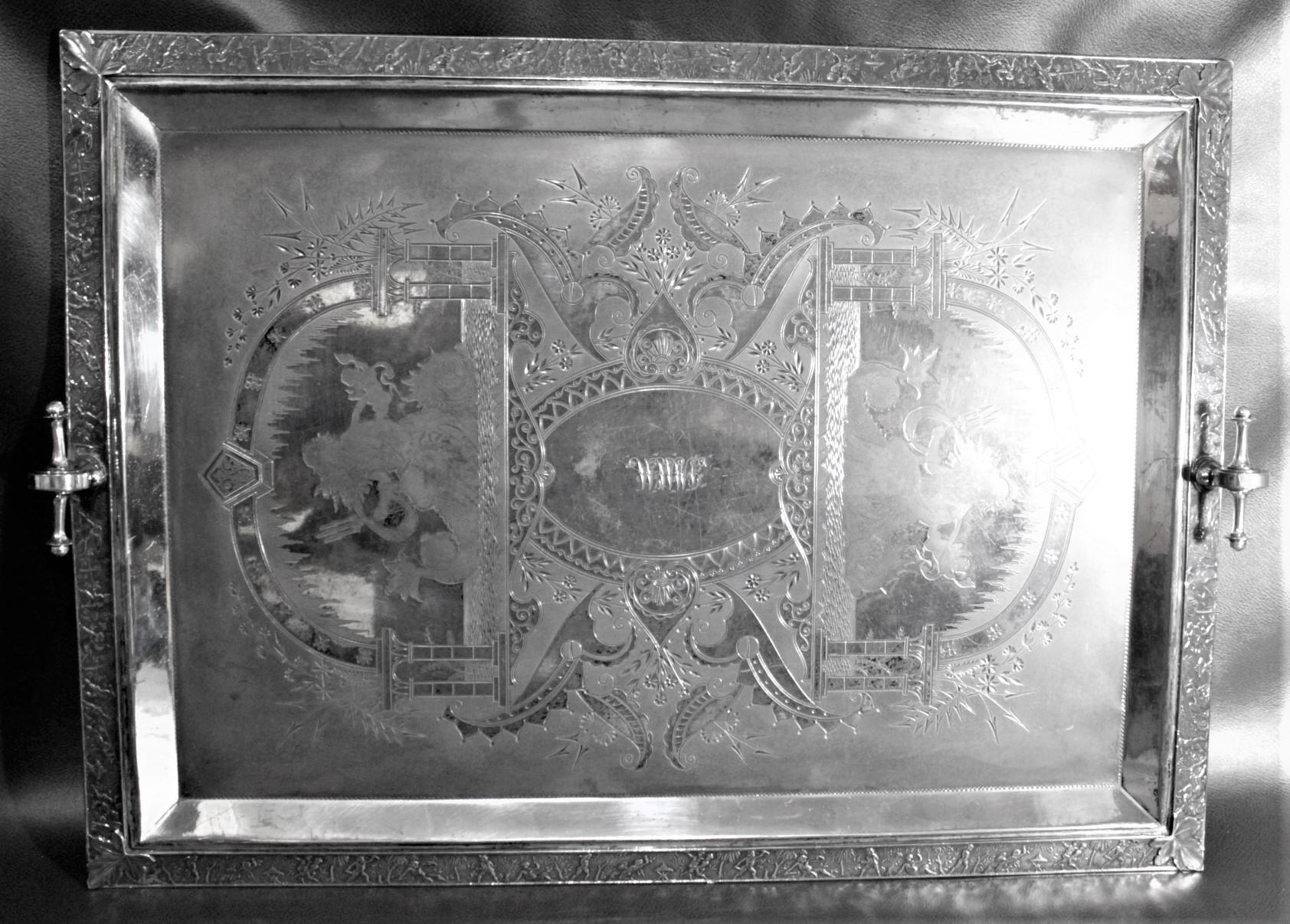 This very large and ornate silver plated serving tray is unsigned, but presumed to have been made in the United States in circa 1900 in the period Aesthetic Movement style. The tray is divided into two mirror image vignettes of presumably some form