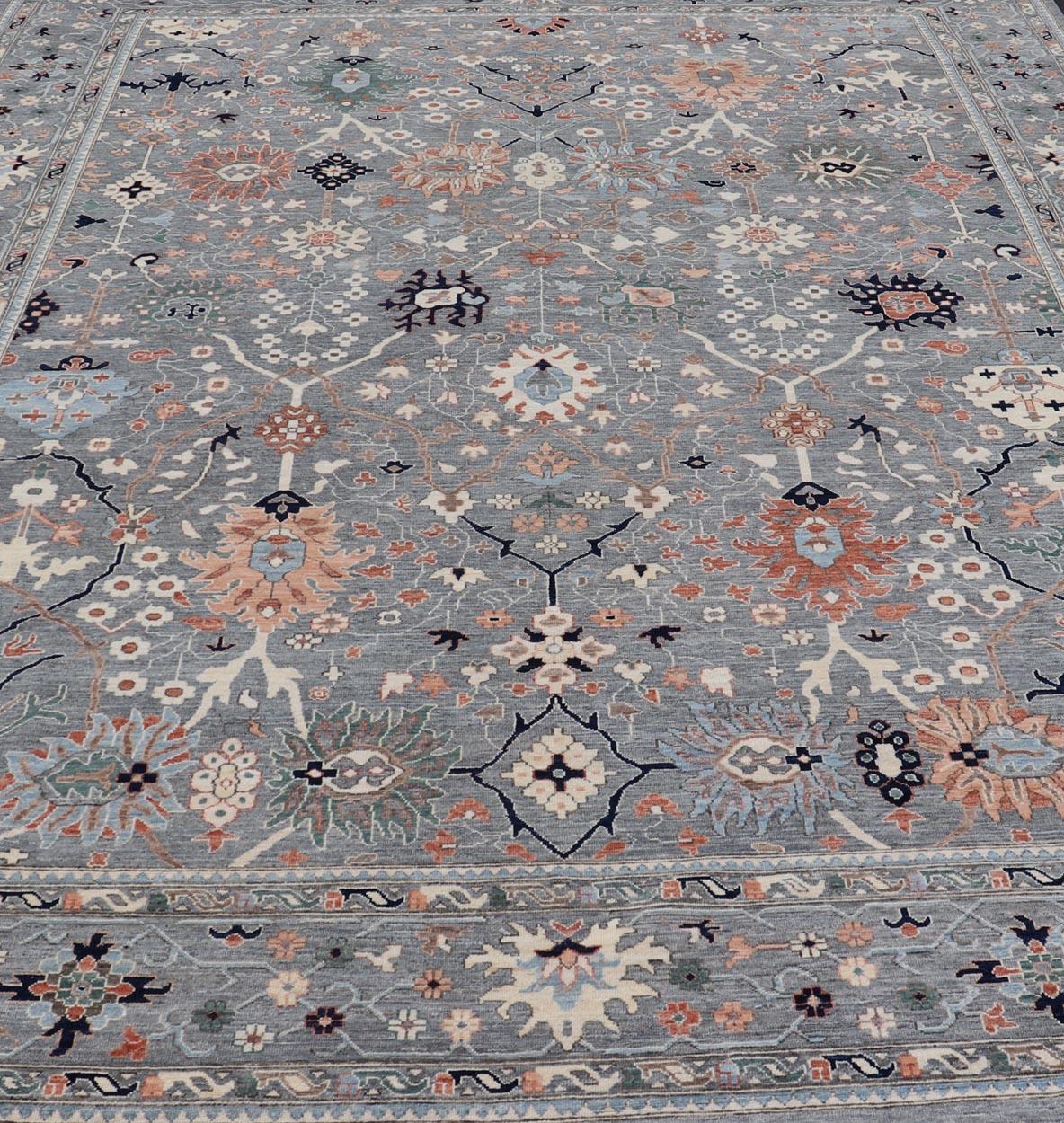 Oushaks are known for their floral-inspired motifs, this piece has a more modern feel with bright corals, pinks, greens and creams that stand out behind a gray background.  This particular piece accents rich, dark blues within the field and border,