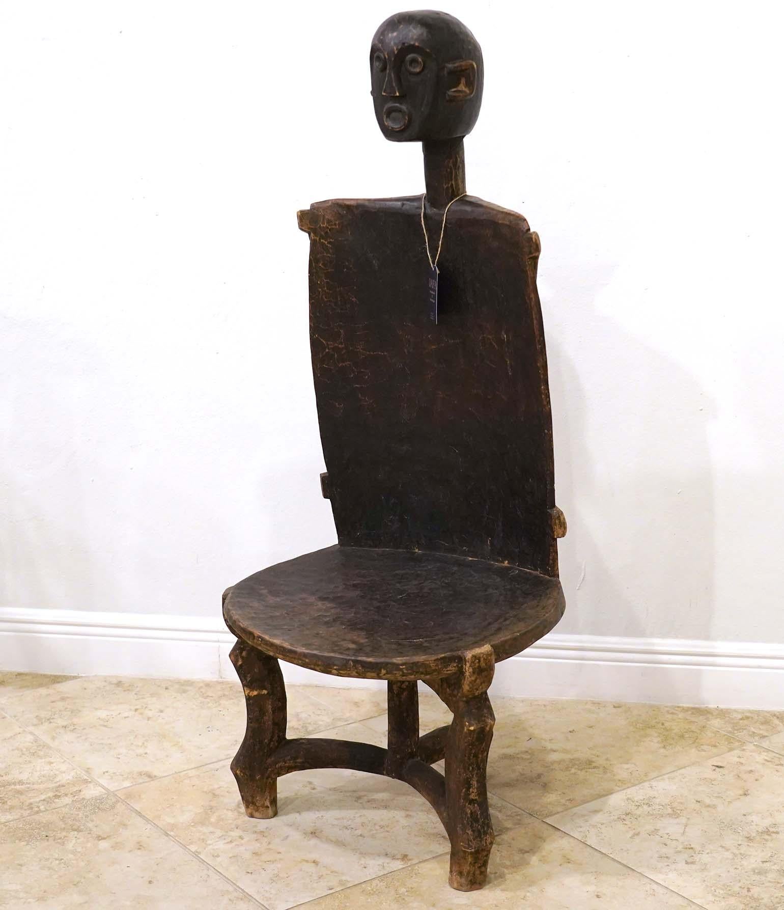 Carved out of one piece of wood this sculptural Chief's Throne Chair represents a long standing tradition among the Nyamwezi people of Tanzania. A male figure carved in haut relief his head protruding over the backrest is clinging with hands and