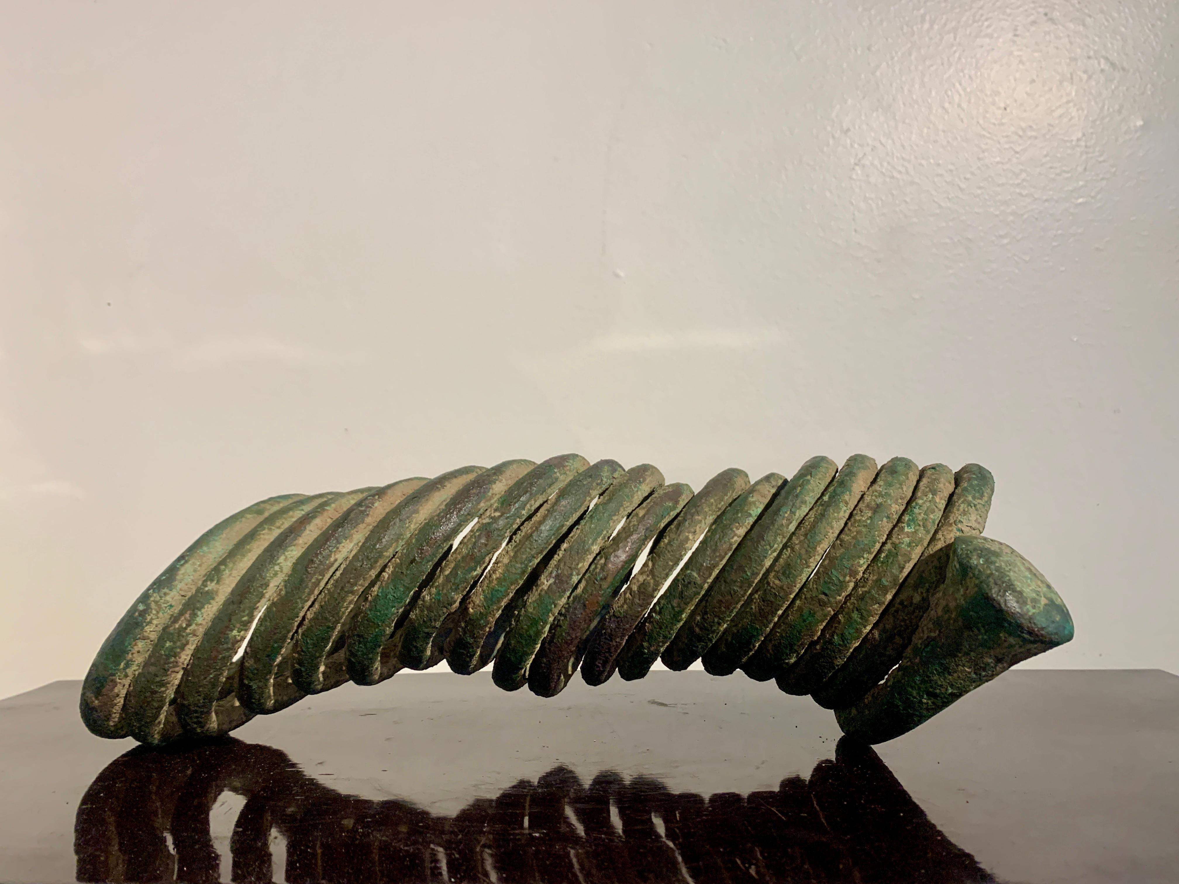A large and impressive coiled copper manilla currency piece with gorgeous patina, early 20th century, Igbo People, Nigeria.

The striking manilla currency crafted of heavy copper forged into a spring form with eighteen coils, and terminating in