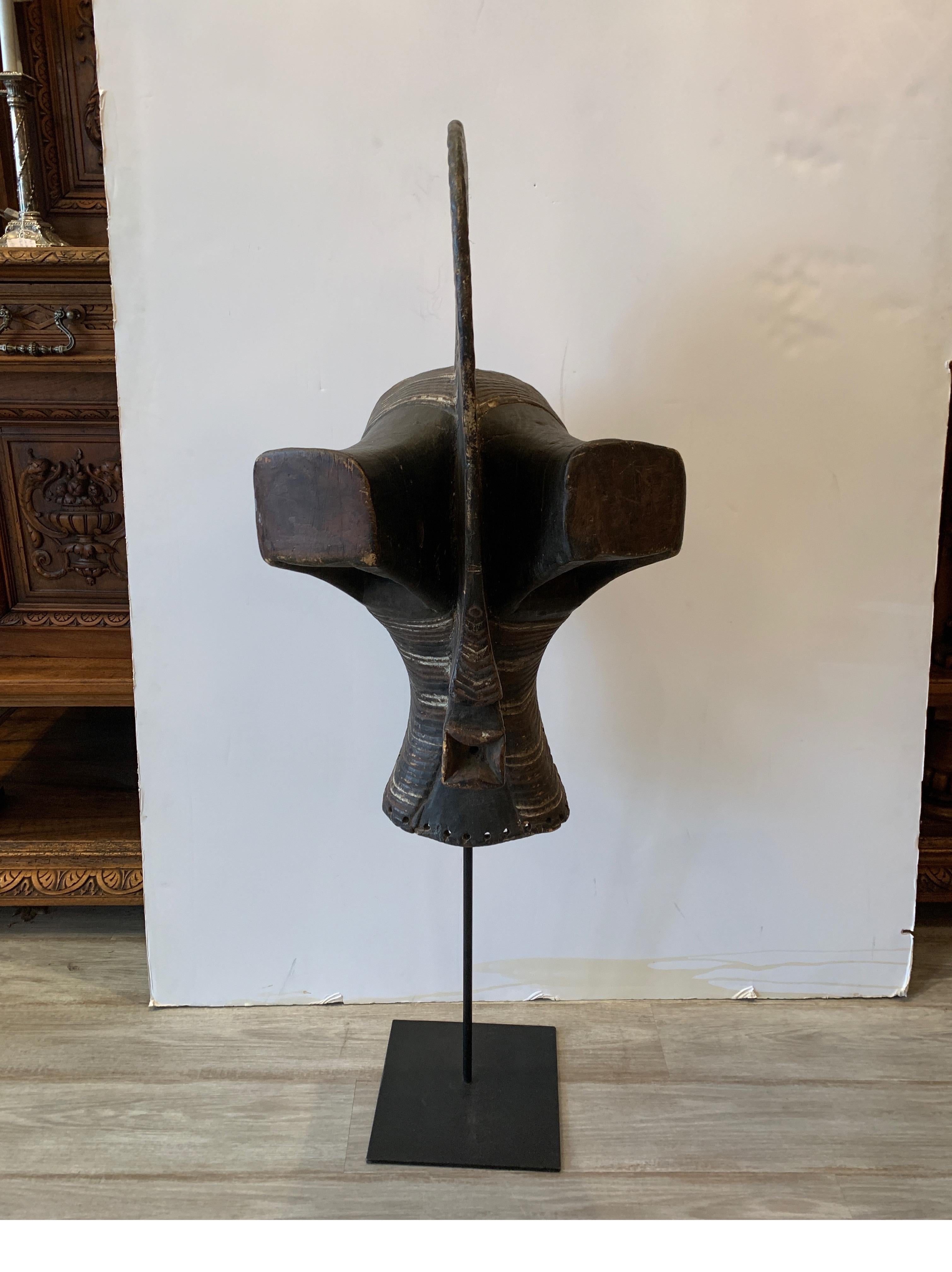 Maschera africana intagliata a mano molto elegante su un supporto personalizzato. La parte anteriore ha una superficie molto strutturata con dettagli dipinti, c'è qualche restringimento e separazione nelle cuciture a causa dell'età. La base in