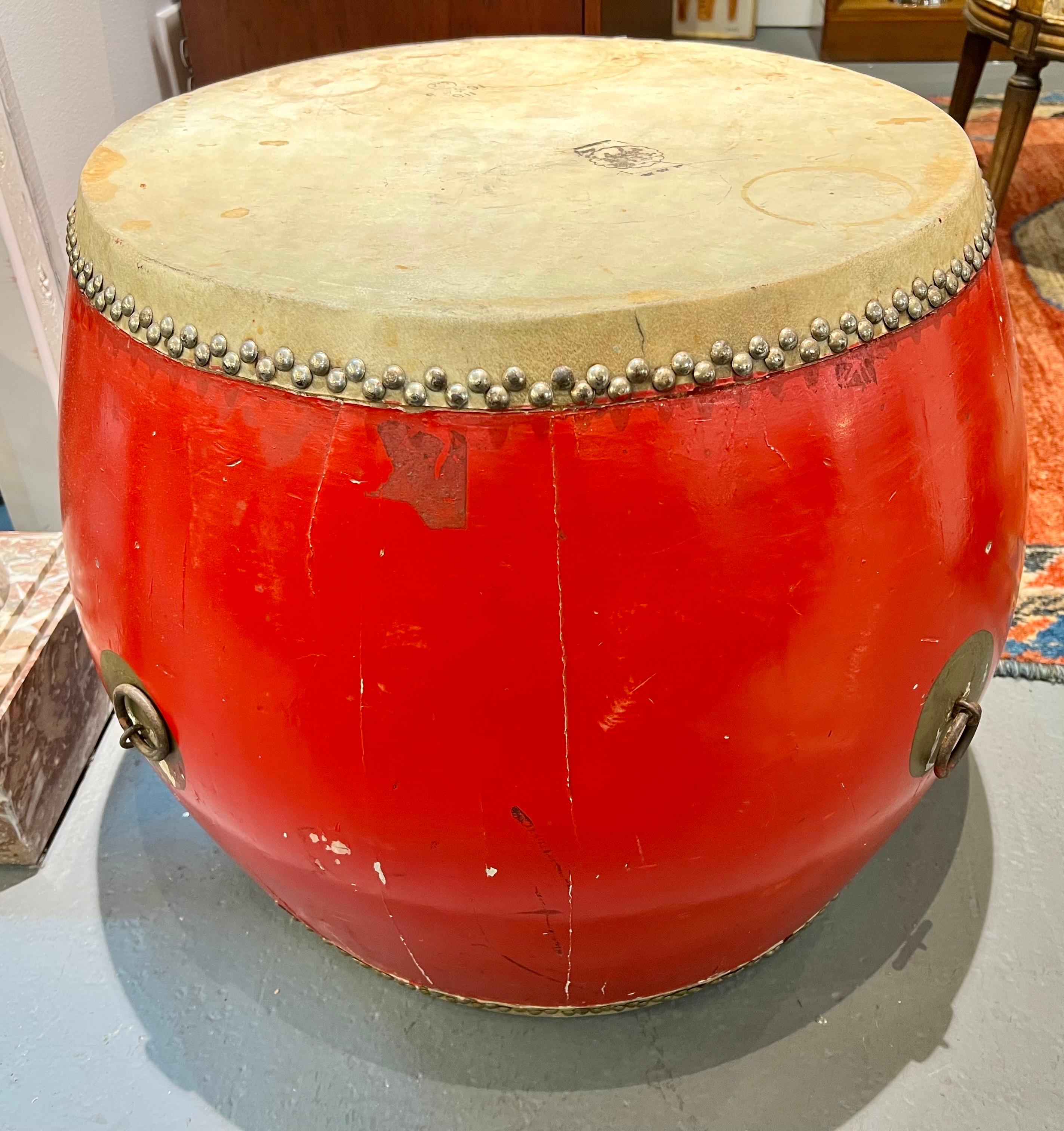 Red lacquered African drum table with brass handles and goatskin top with brass nailheads all around. Large enough to use as an end table.